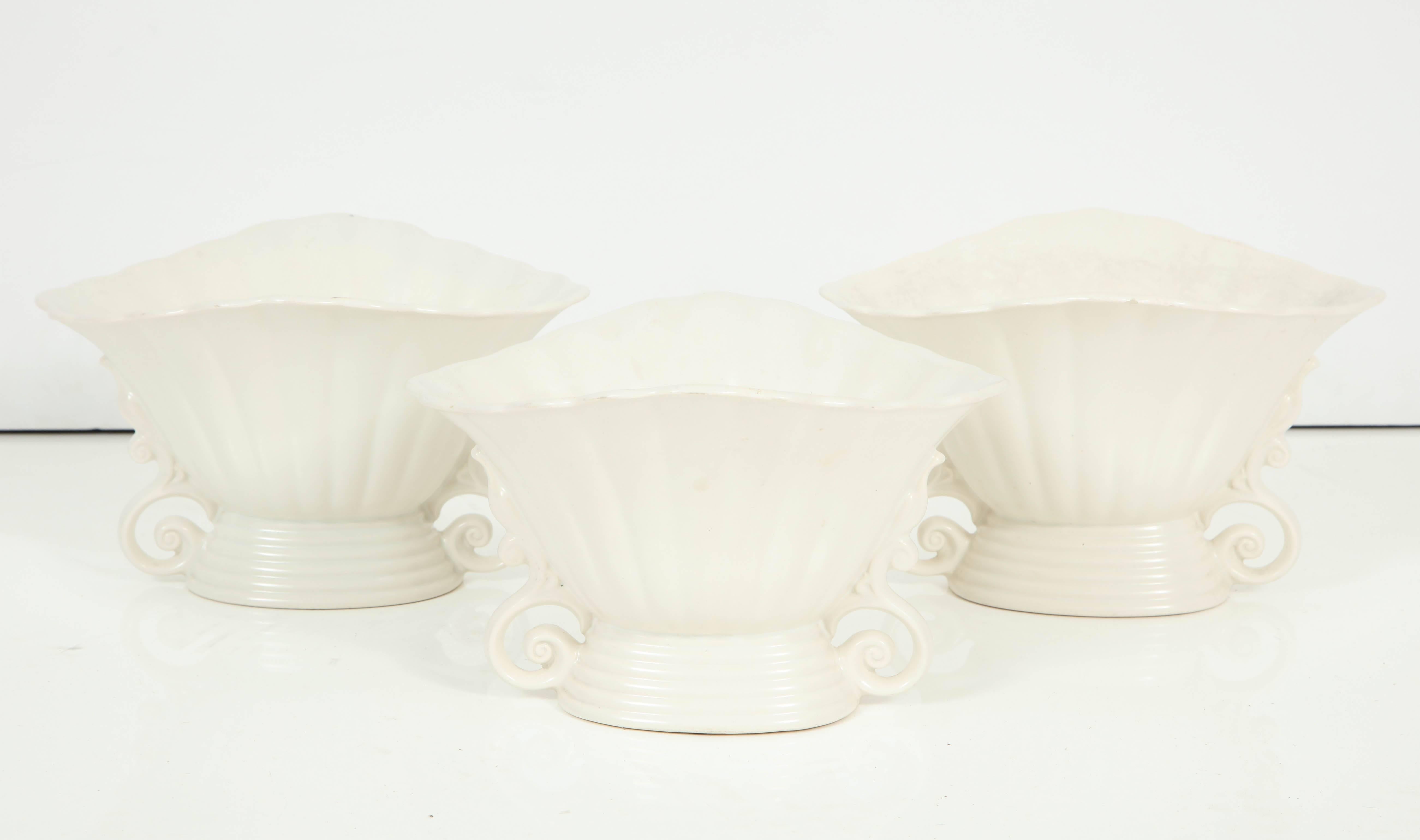 A set of three white mat-glazed Wade vases. England, circa 1930. The scalloped rim and lovely sculptural details make these vases unique, he perfect accent piece in a kitchen or anywhere!
  