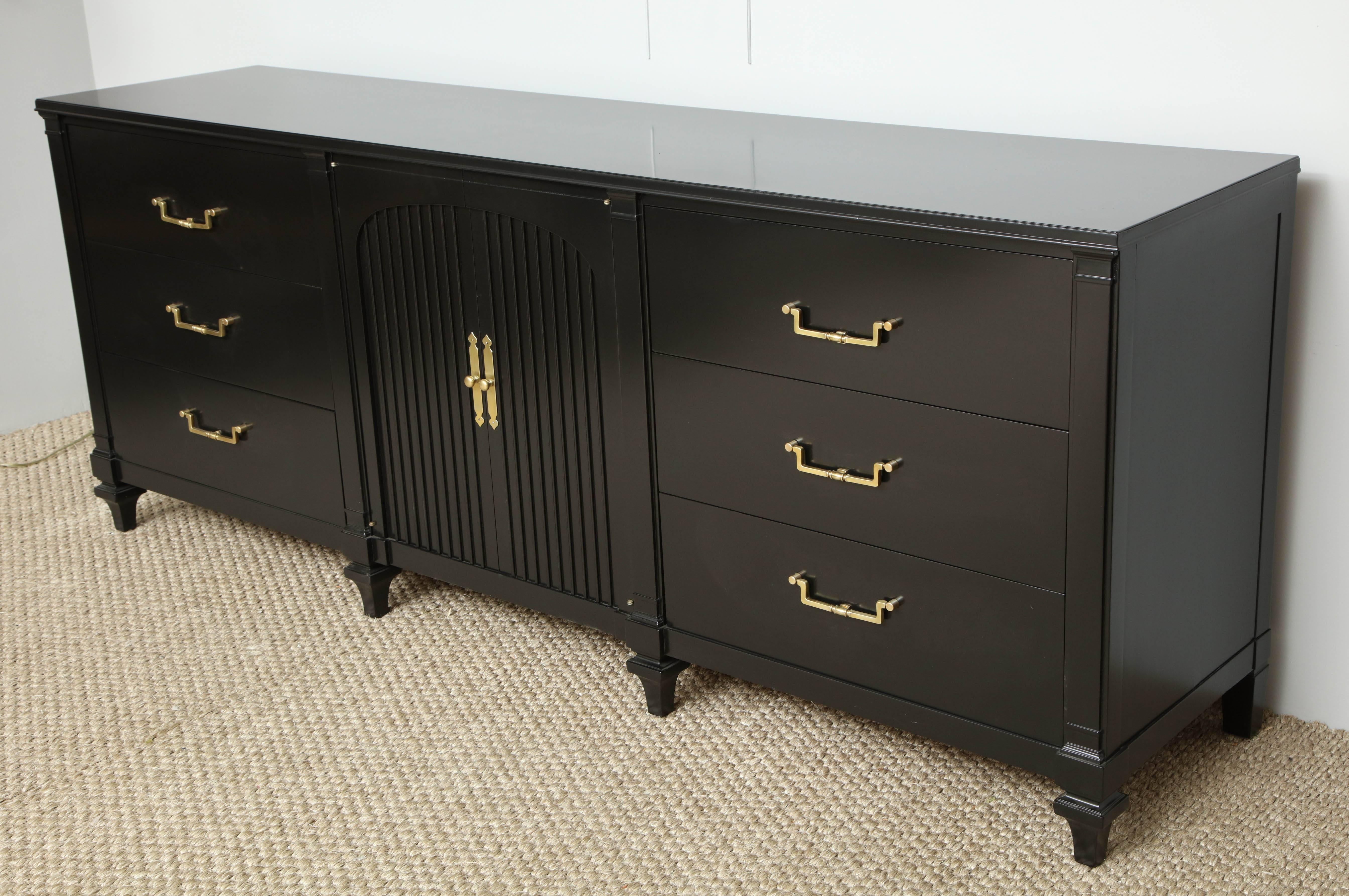 This long dresser produced (and stamped) by John Widdicomb has both form and function. Lacquered in black satin, this great looking piece features two paneled center doors, opening to expose three pull-out drawers and three large drawers on either