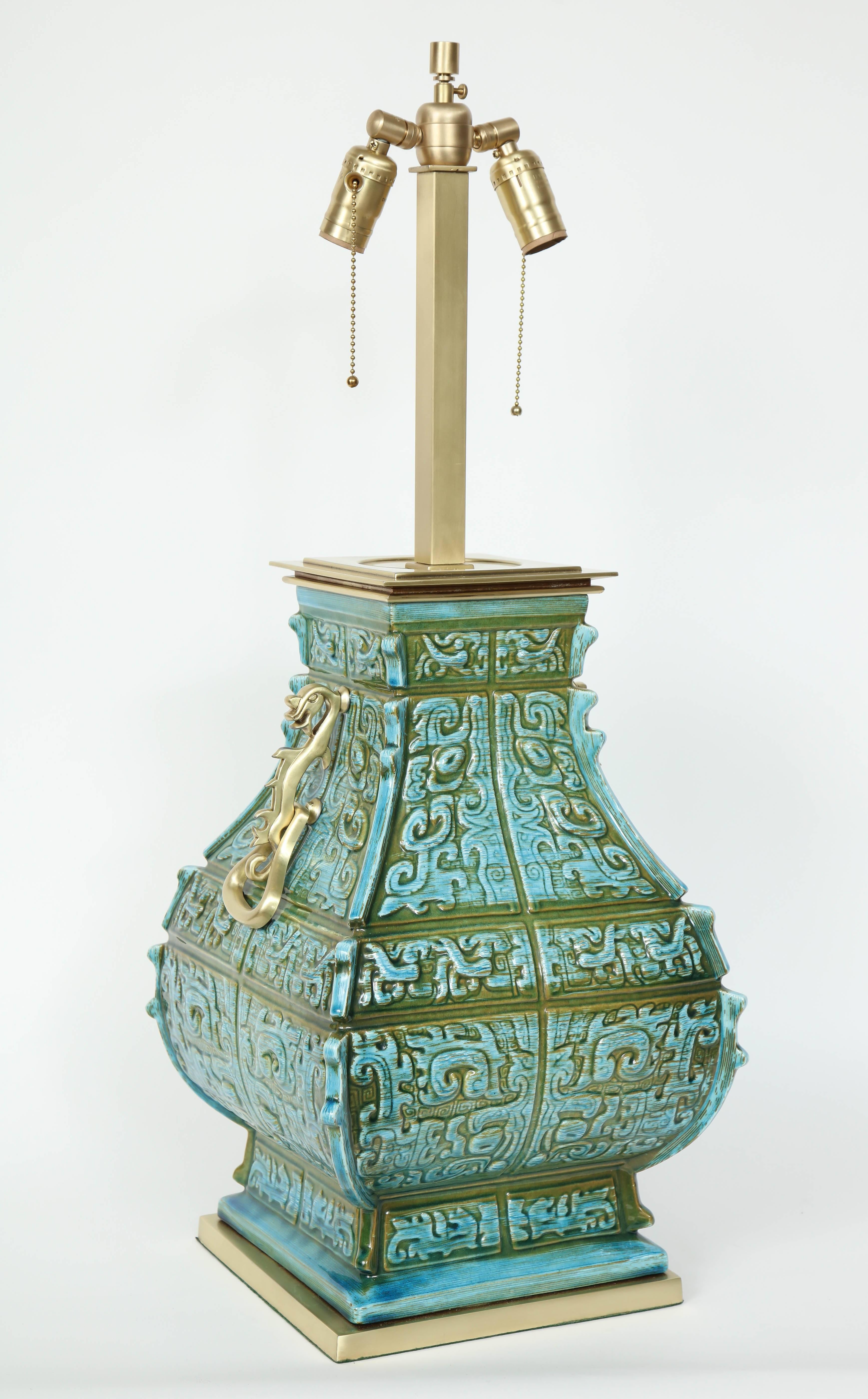 Fantastic pair of Tony Duquette inspired porcelain lamps in muted colors of moss green and sky blue glaze with satin brass door knocker accents on sides while sitting on satin finished brass bases. Lamps have been rewired for use in the USA.