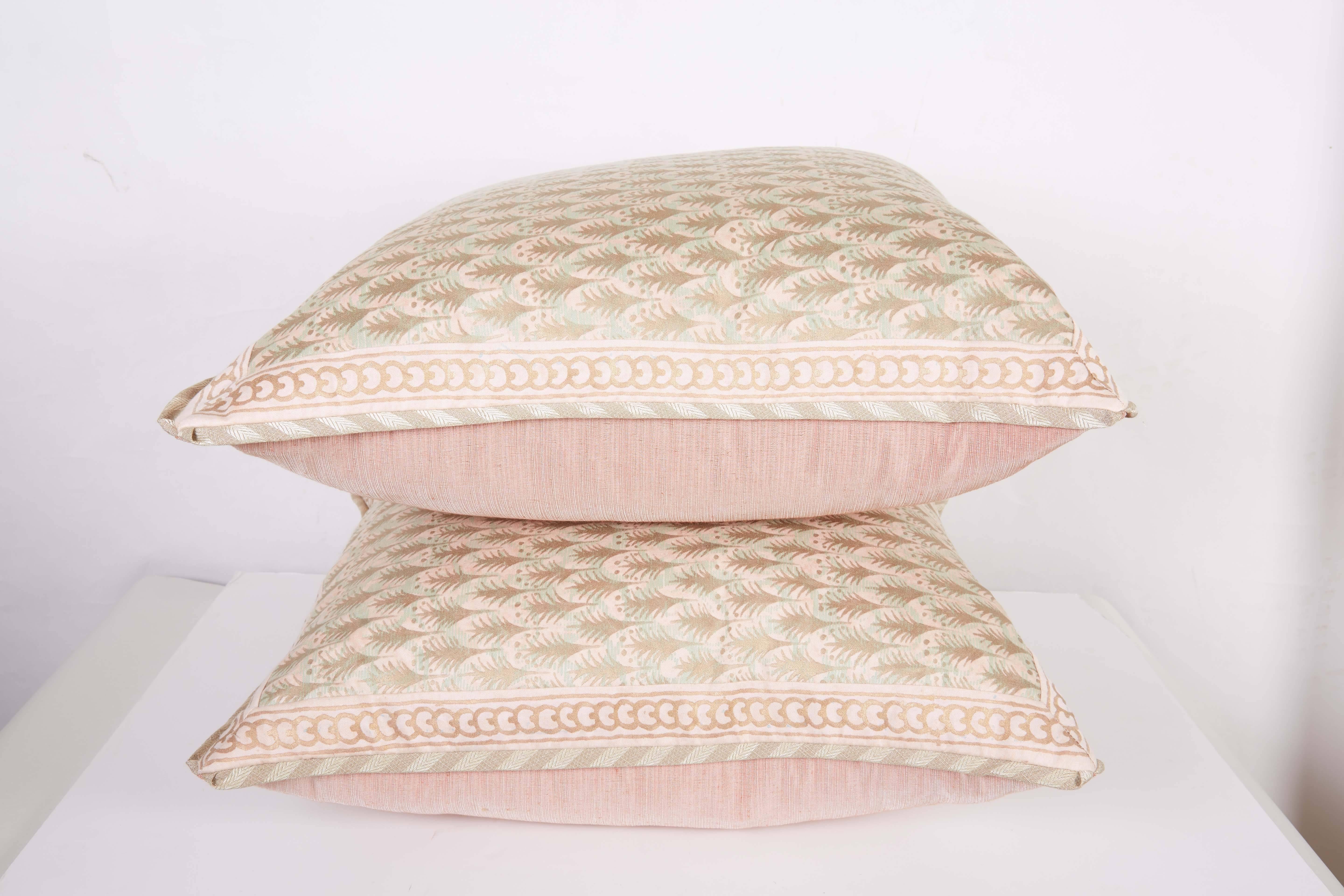 A pair of Fortuny fabric cushions in the Puimette pattern, shell pink, powder blue and gold color way with silk bias edging and Clarence House silk blend backing material, the pattern, a 15th century Persian design with feather motif and stylized