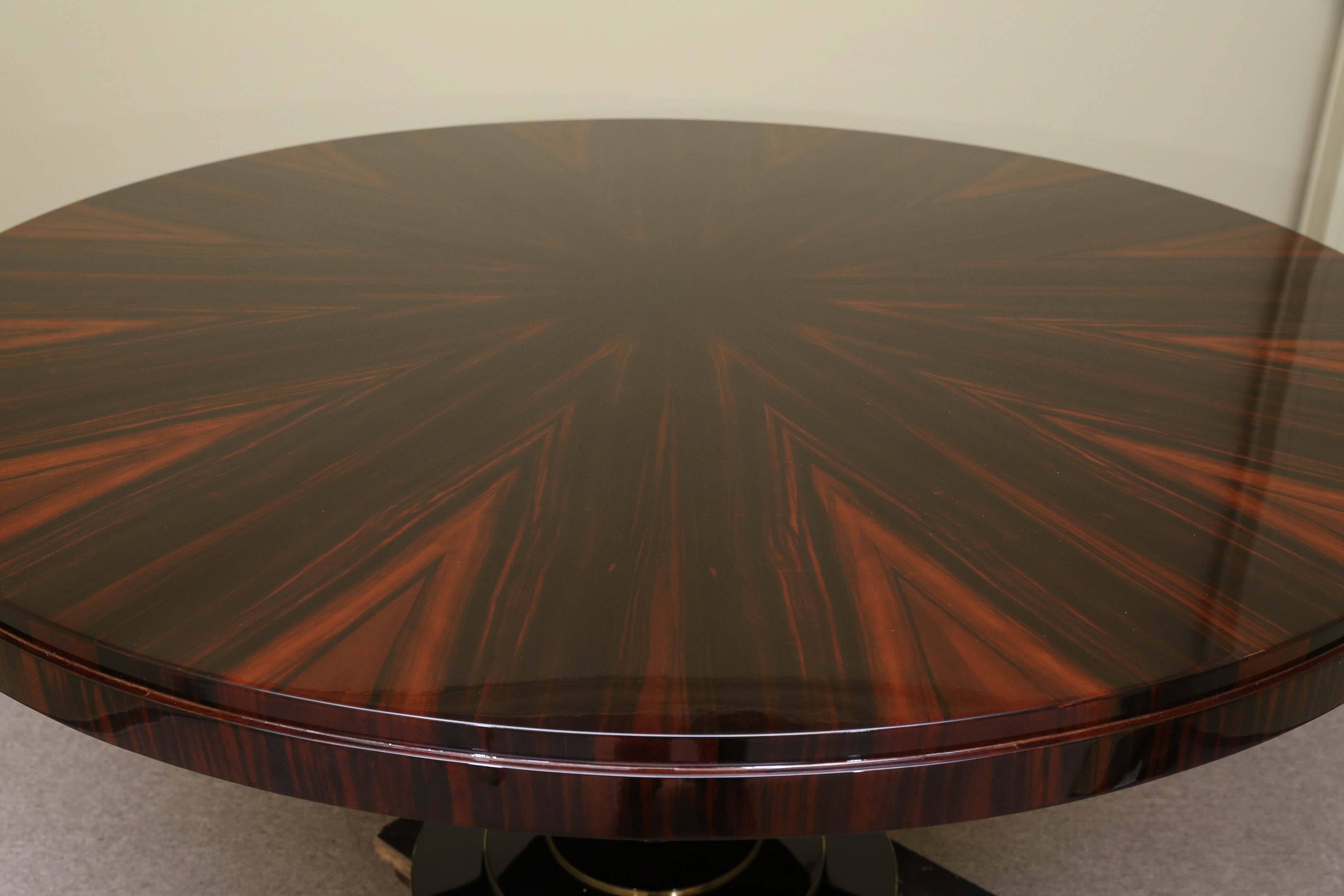 Round tabletop displays beauty of the high quality Macassar wood. It is supported by the slim leg that is attached to the round base. The base has brass trimming around it. 
Re-polished. Condition is excellent. 

 France, circa 1930s
Measures: