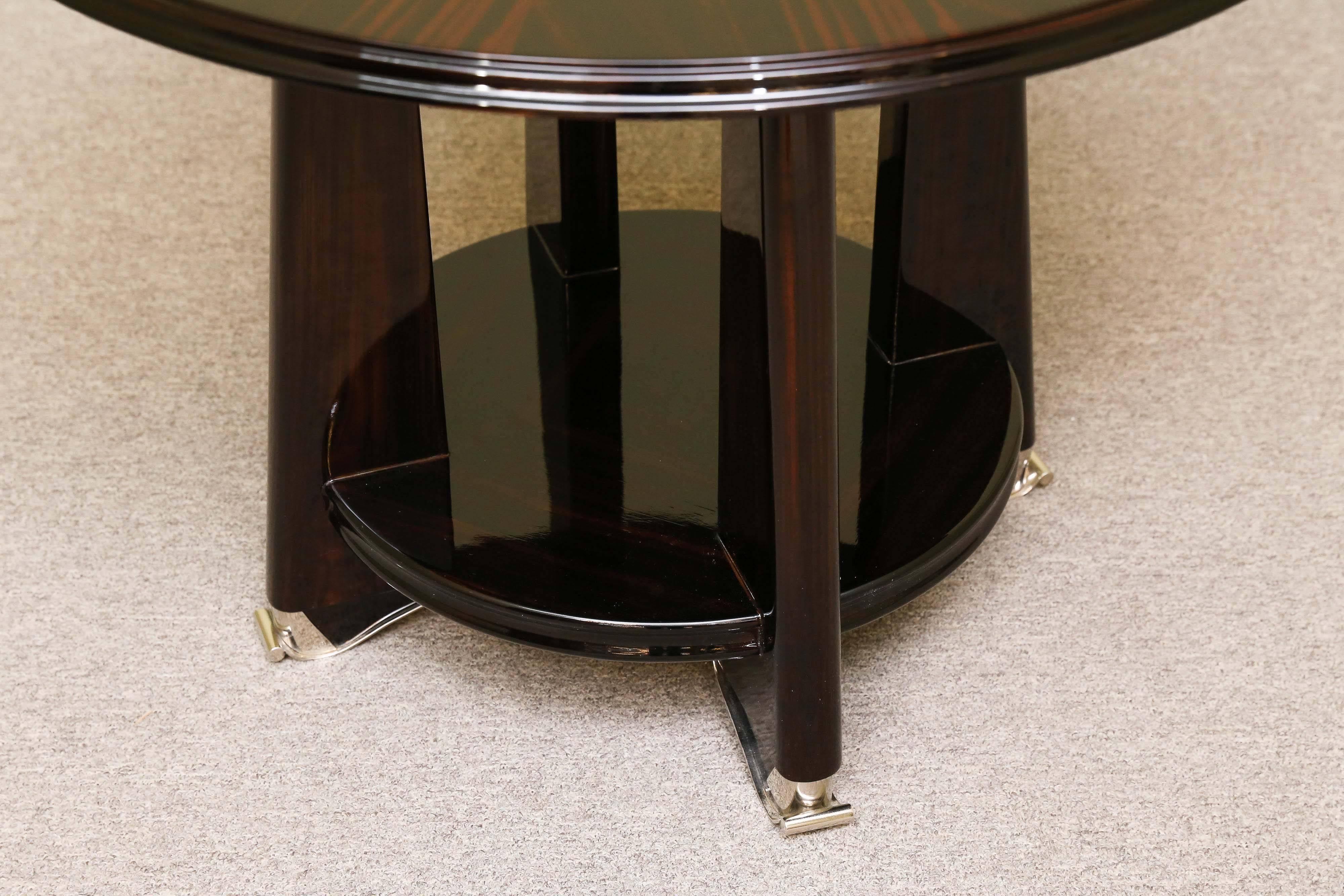 Side table is made out of Macassar wood and the tabletop is presenting beauty of the wood. The table is elevated by the four wide legs. On the bottom of each leg there is an chrome decorative tip. Four legs are attached to the round shelf that gives