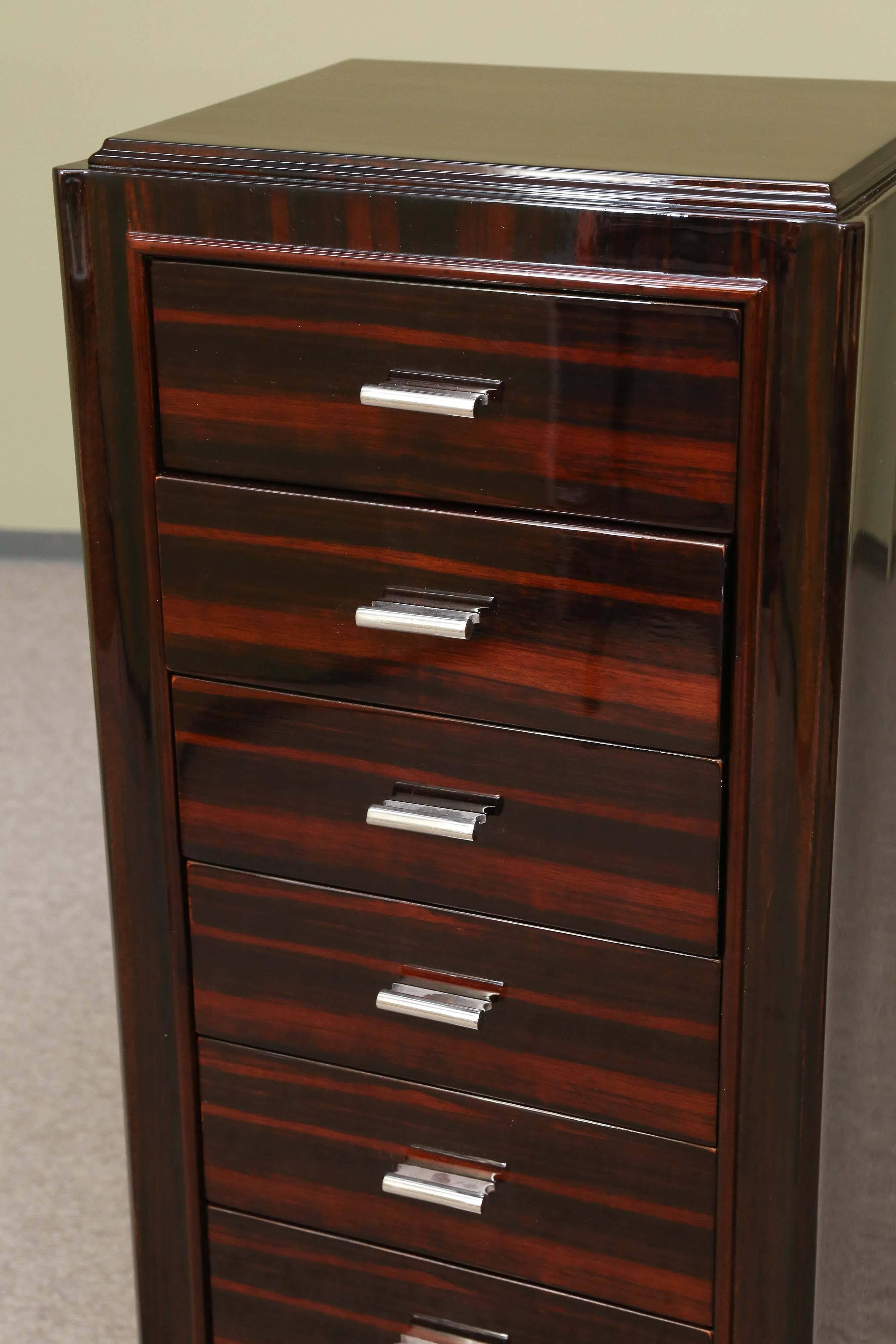 This chest of drawers is build from Macassar and walnut. It has seven spacious drawers and nice wooden trimming on the edges. The chest is elevated by 4 elongated legs, surrounded at the bottom with a chrome decorative elements.
Condition is