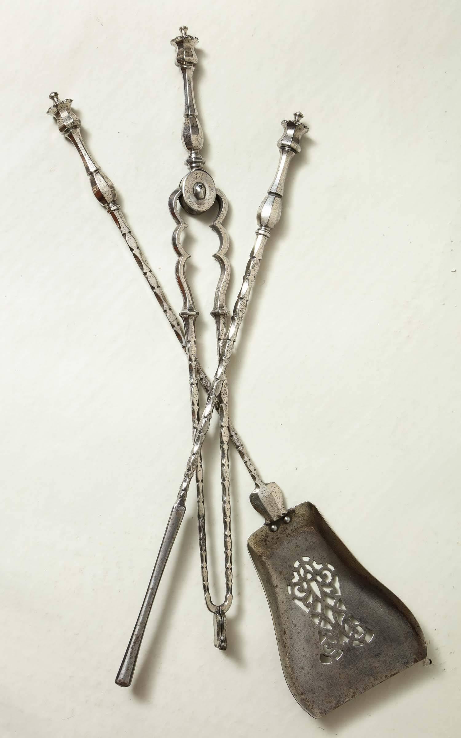 Raffinato set di utensili da fuoco in acciaio lucido William IV, con bordi sfaccettati, le terminazioni con disegno stilizzato a testa di papavero, la pala con decorazione a traforo e tutti lavorati con precisione e grazia.  Inghilterra, circa 1835.