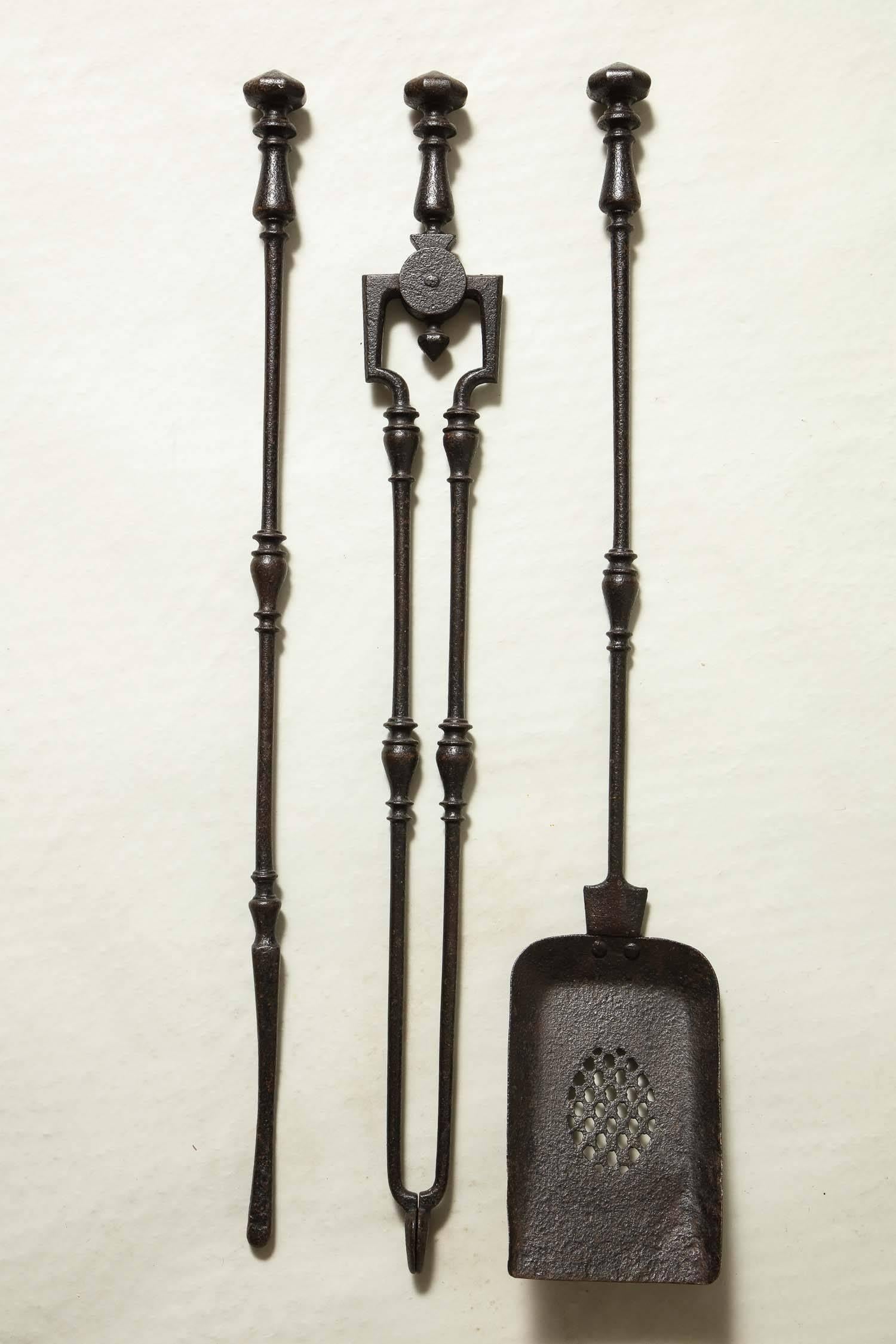 Good set of three George III period blackened steel fire tools comprising a pair of tongs, shovel and poker, all with faceted hexagonal handles, all with balustrade collars in centre of shaft, the shovel with pierced oval decoration.