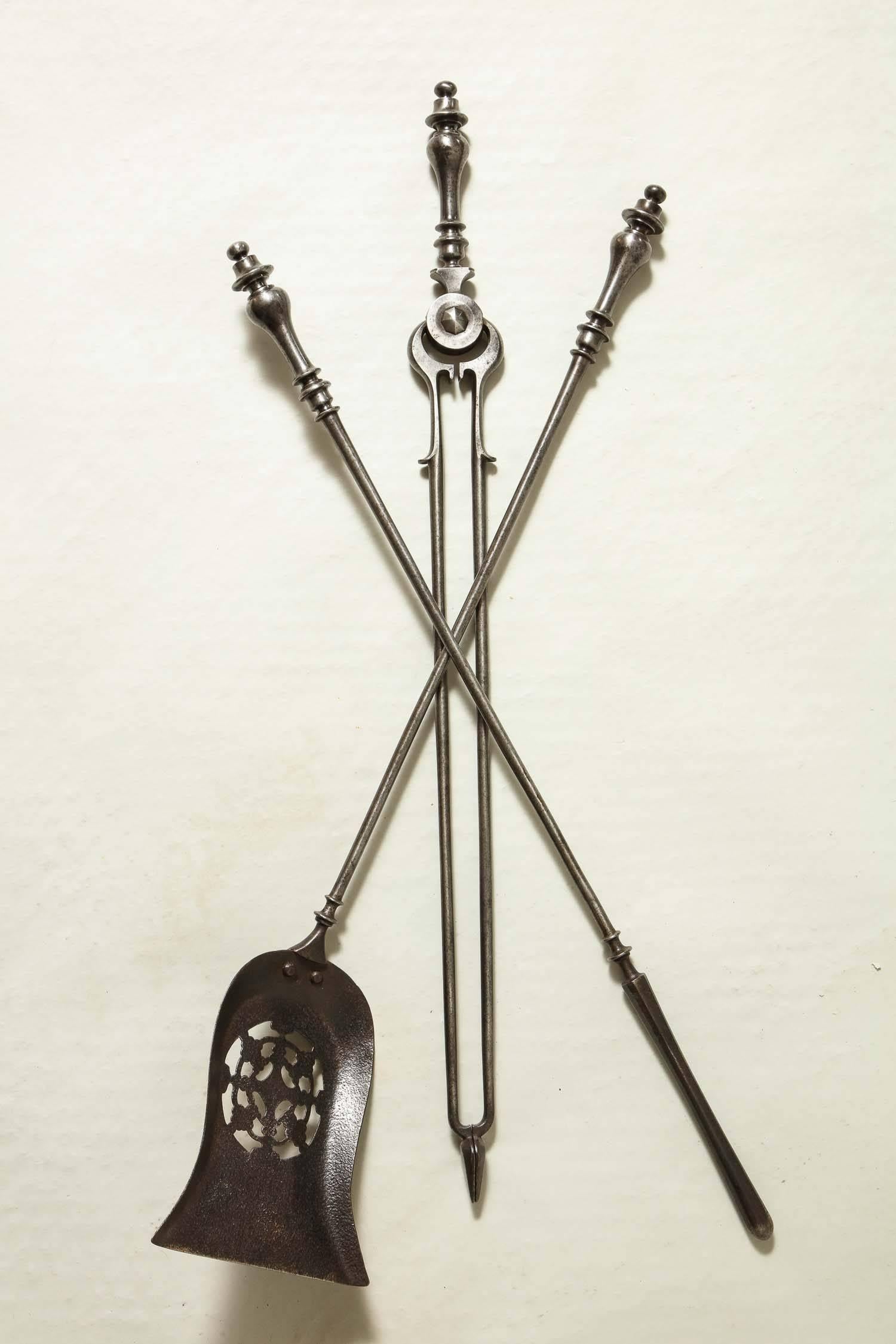 Fine set of 19th century gunmetal steel fire tools comprising a shovel, pair of tongs and poker, all with turned handles, the shovel with pierced geometric pattern, all with pleasing weight and burnished surface.