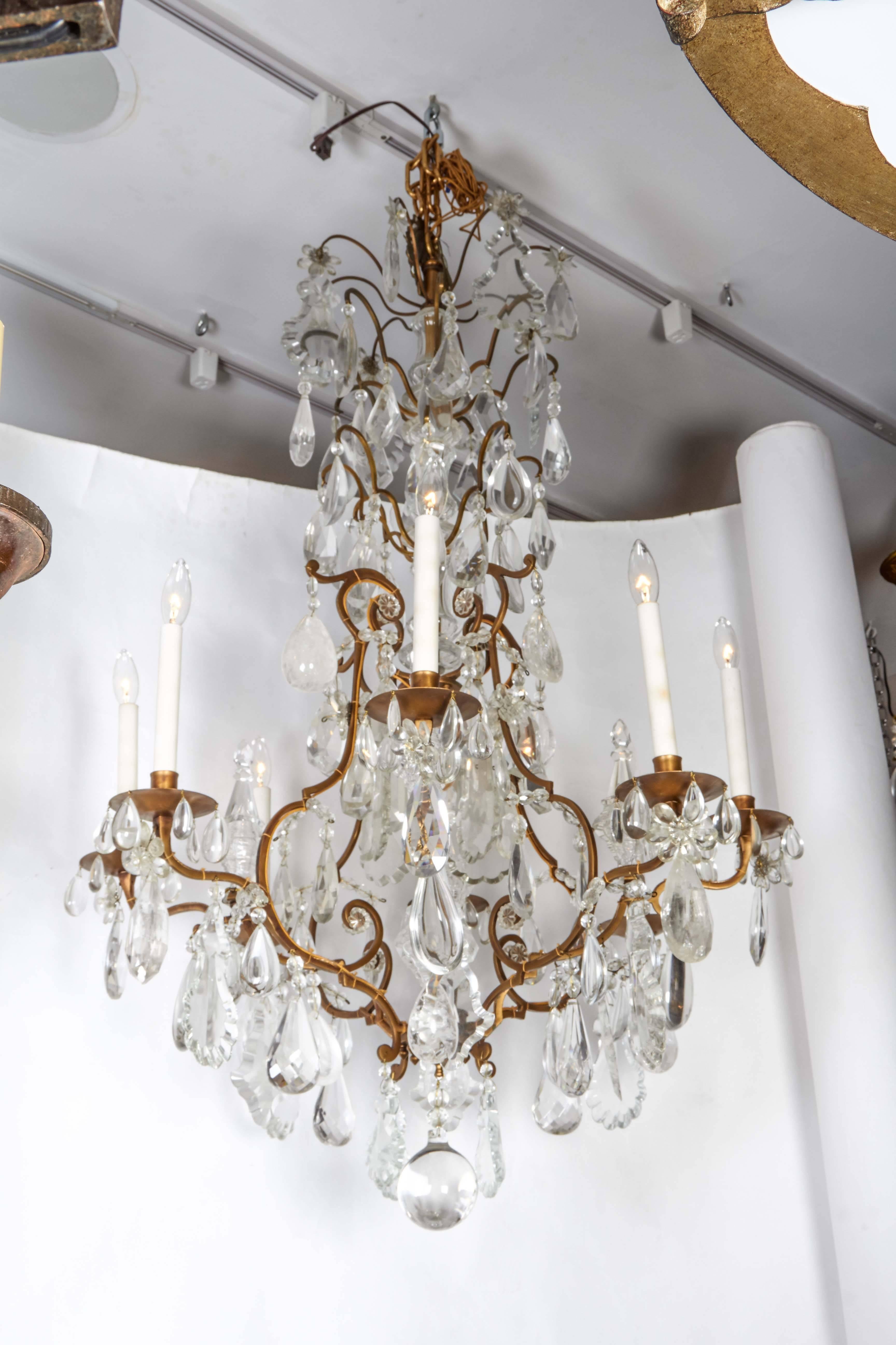An impressive Louis XV style gilt bronze, cut crystal and rock crystal chandelier, the lower part of the central shaft comprised of faceted elements issuing eight scroll branches hung with shaped crystal drops, terminating in a rock crystal