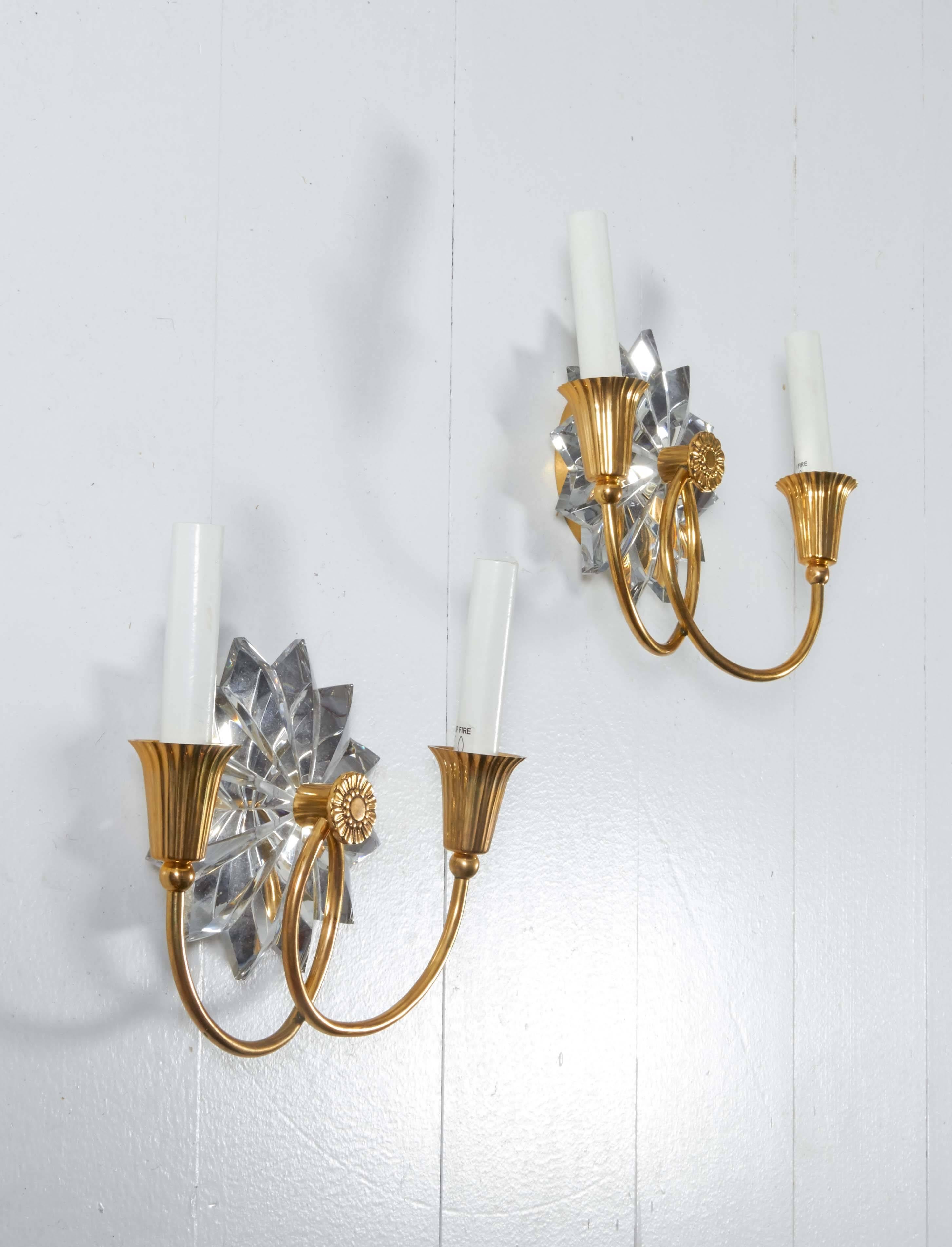 Pair of brass and crystal sconces. The multi-point star motif is an American legacy. The sconce has a twenty-four wedged facets from a solid crystal block. Arms are brass plated. Shades are not included.

Not available for sale or to ship in the