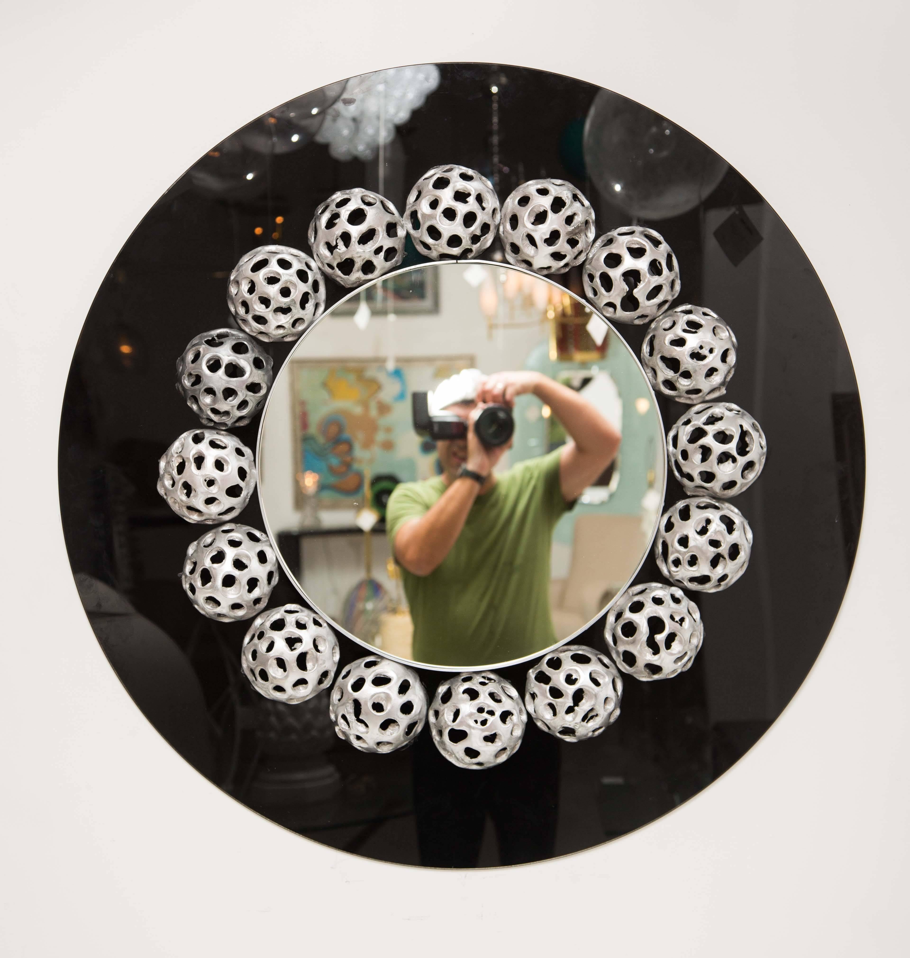 Retro style circular black glass mirror with sphere motif surround.