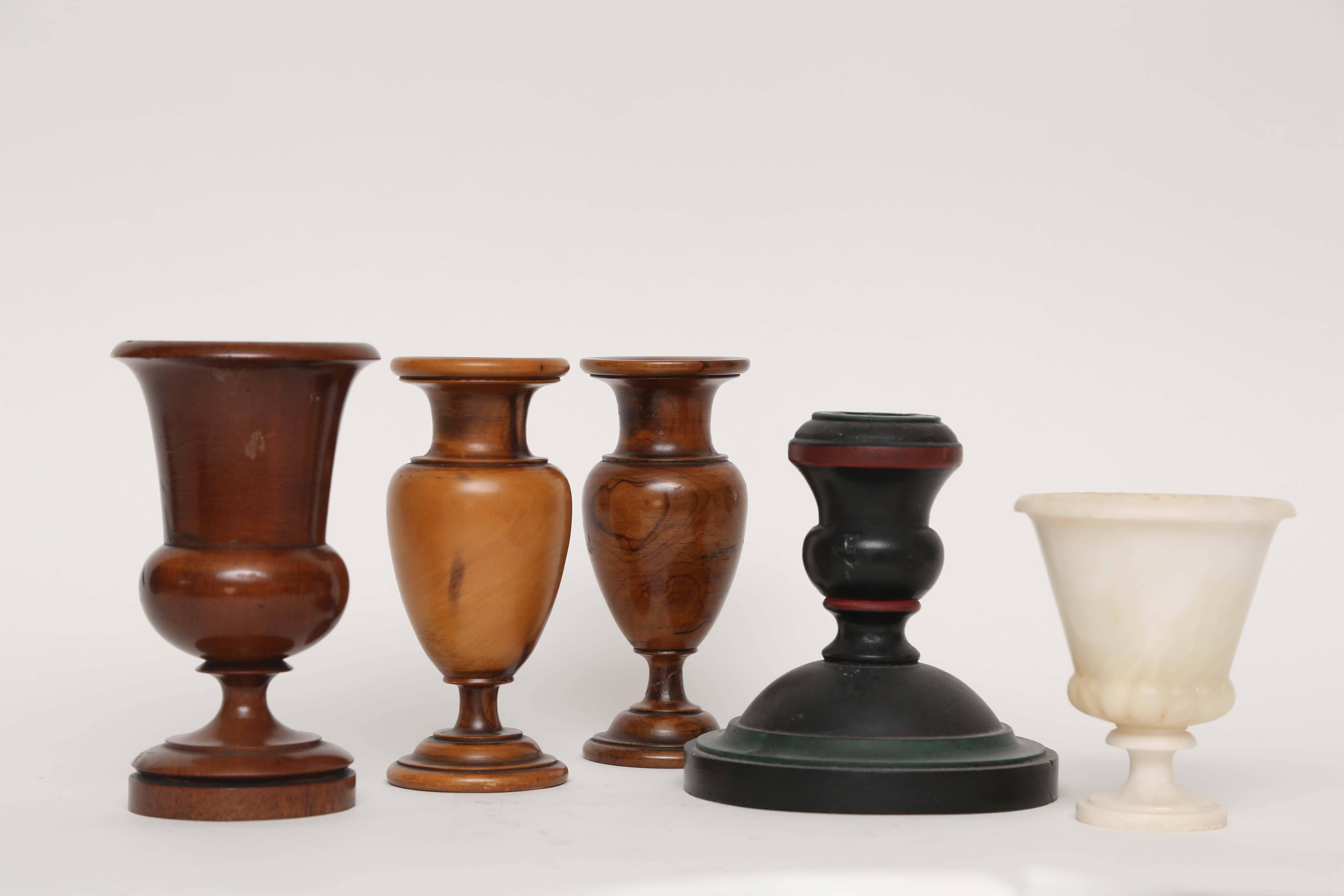 A tabletop collection of turned wood treens, a wood candlestick and an alabaster campana style cup.
