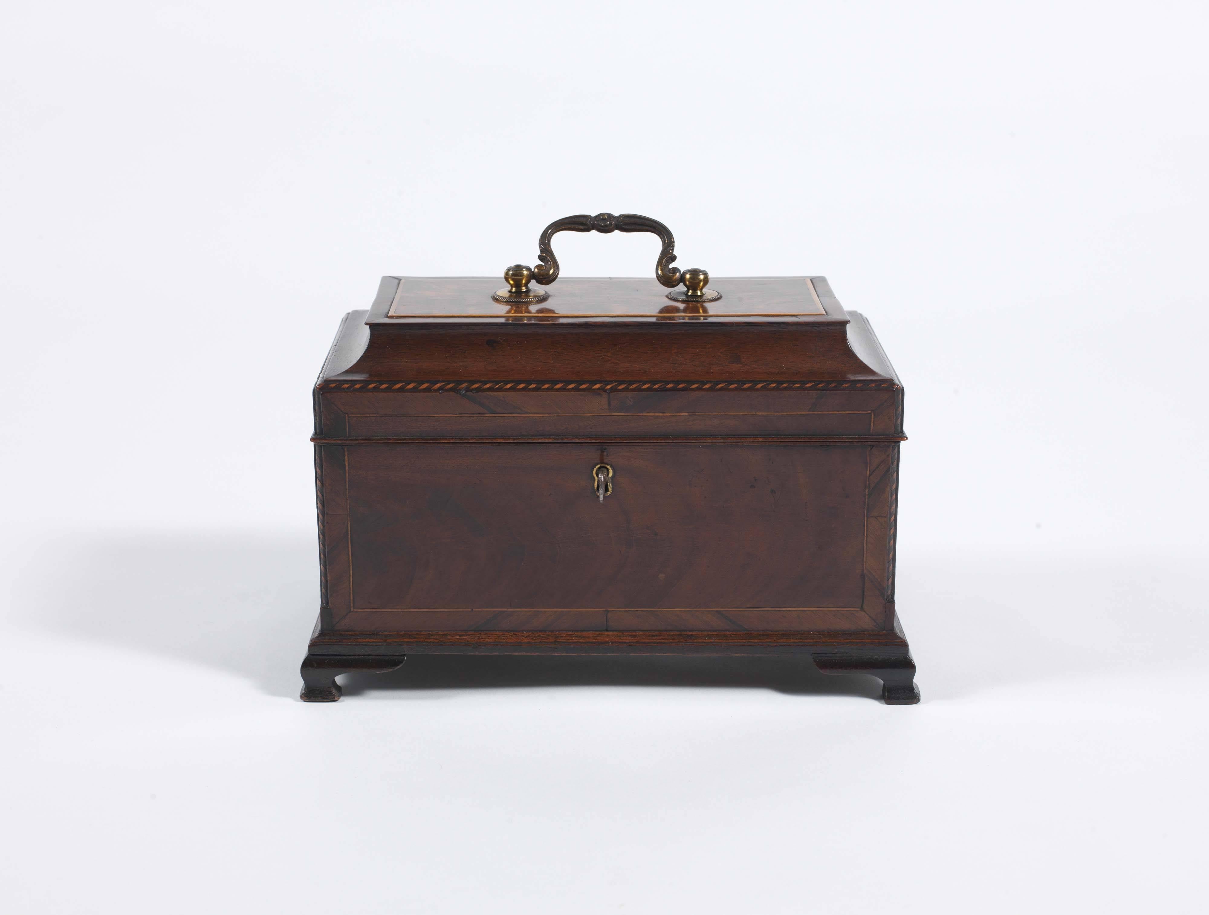 A splendid example with its original gilt metal decorative swan neck handle on moulded hinged lid; the canted corners with boxwood and ebony feathered inlay, the caddy with boxwood stringing, standing on wonderful ogee bracket feet. The interior