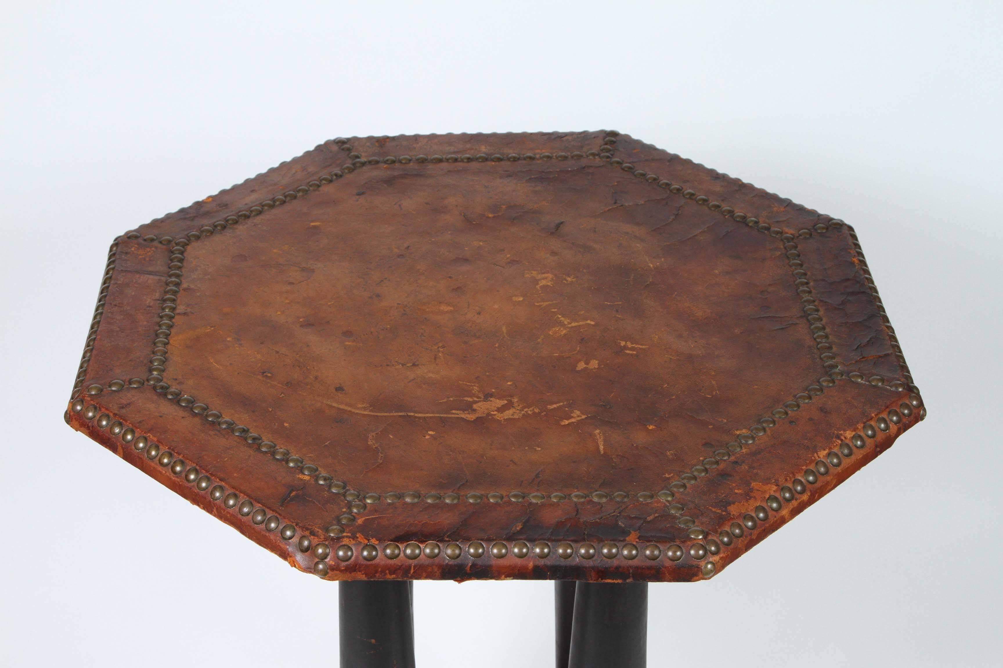 French Art Deco leather table.
Unique shape antique octagonal wood table with leather wrapped top with studded detail that sits on four tapered black pedestals that connect to a smaller octagonal base also covered in a studded leather.
Great