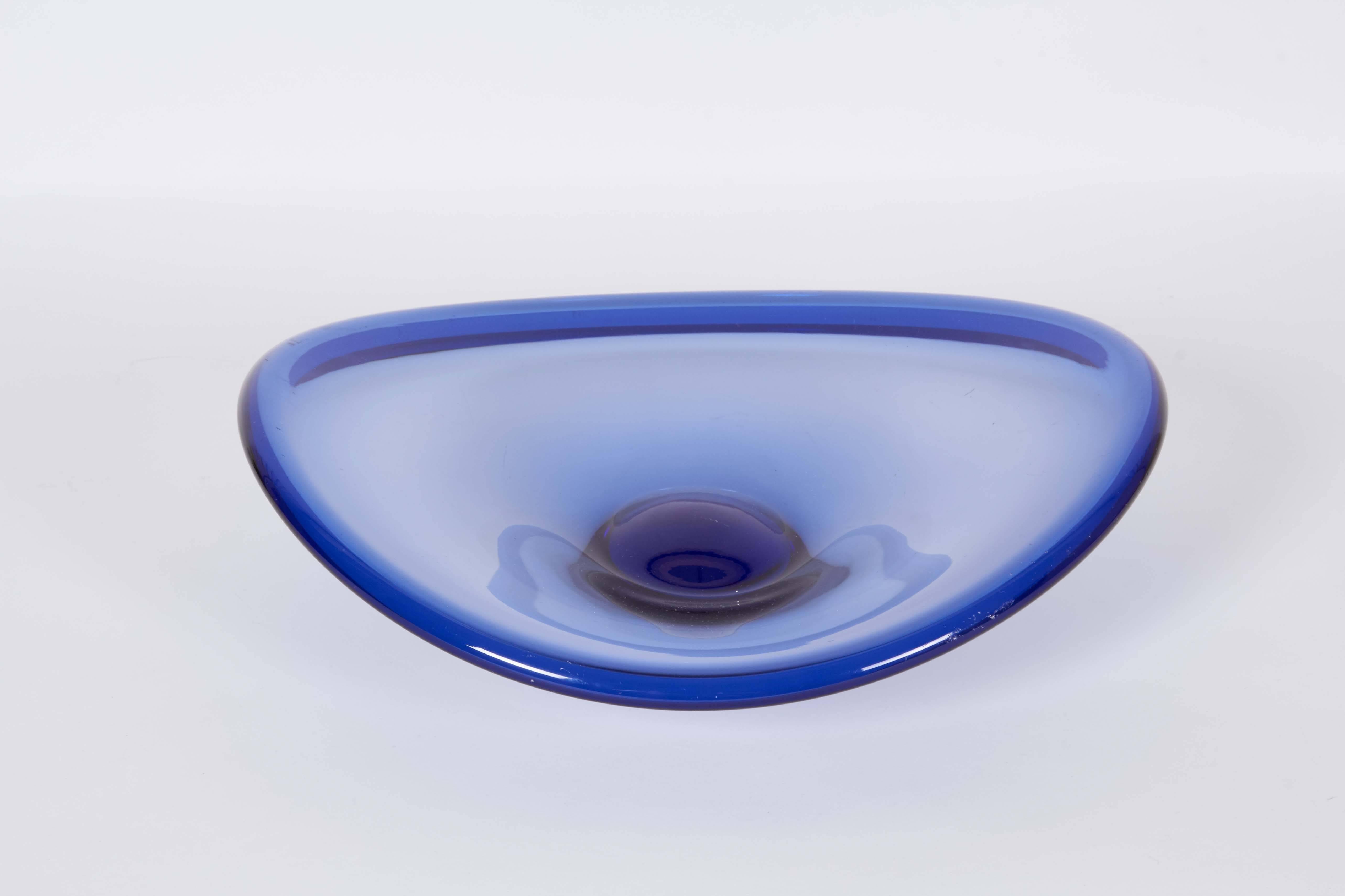 A Scandinavian Modern blown glass 'Selandia' dish, designed by Per Lutken for Holmgaard, produced circa 1950s-1960s, in cobalt blue with abstract curved rim and convex center. Markings include [Holmgaard], Lütken's signature, numbered [14595] to the