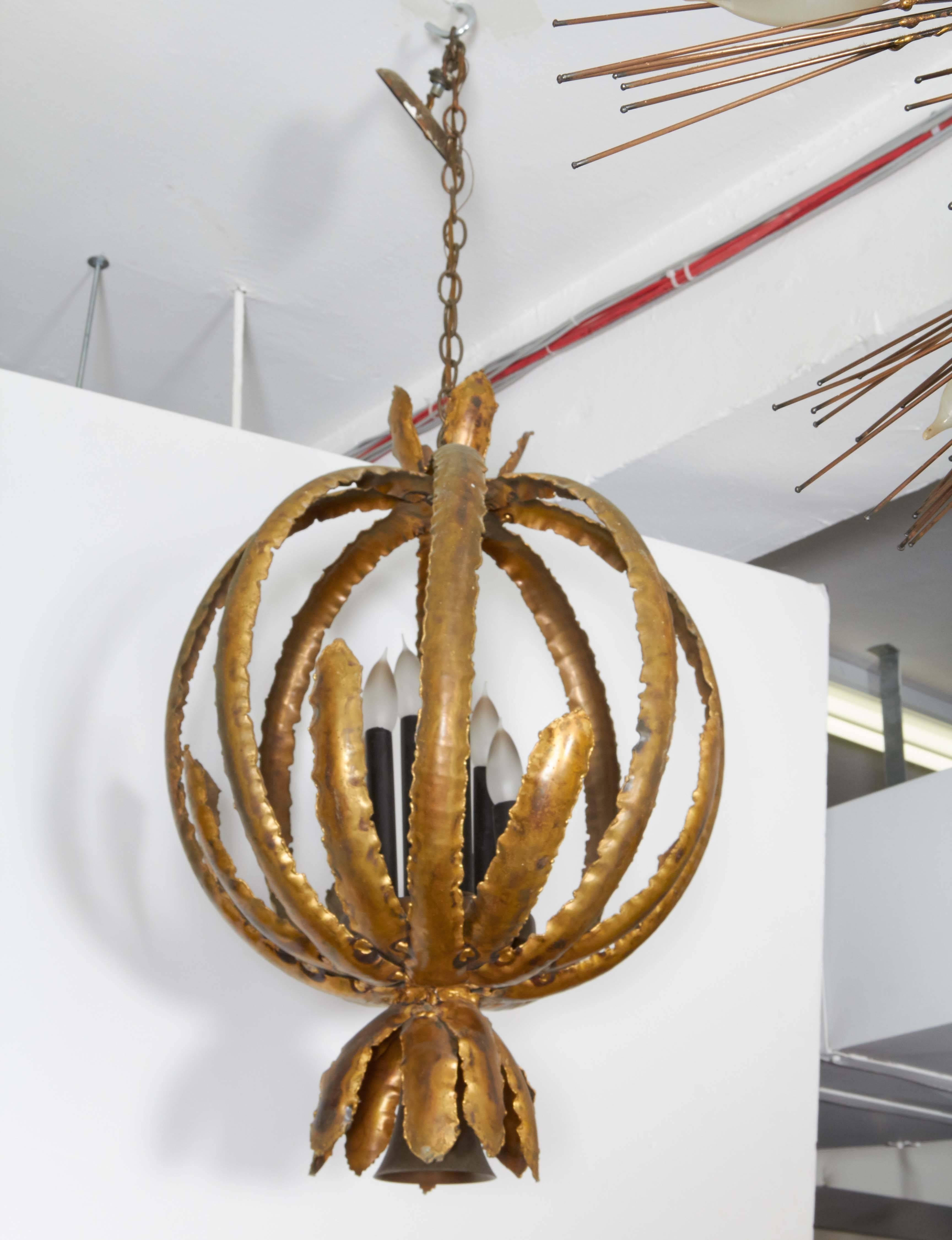 A Brutalist style chandelier by Tom Greene, manufactured by Feldman Lighting circa 1970s, with sheets of torch cut and soldered enameled metal, formed into a pod shape, surrounding six staggered lights. Dimensions provided reflect body. Very good