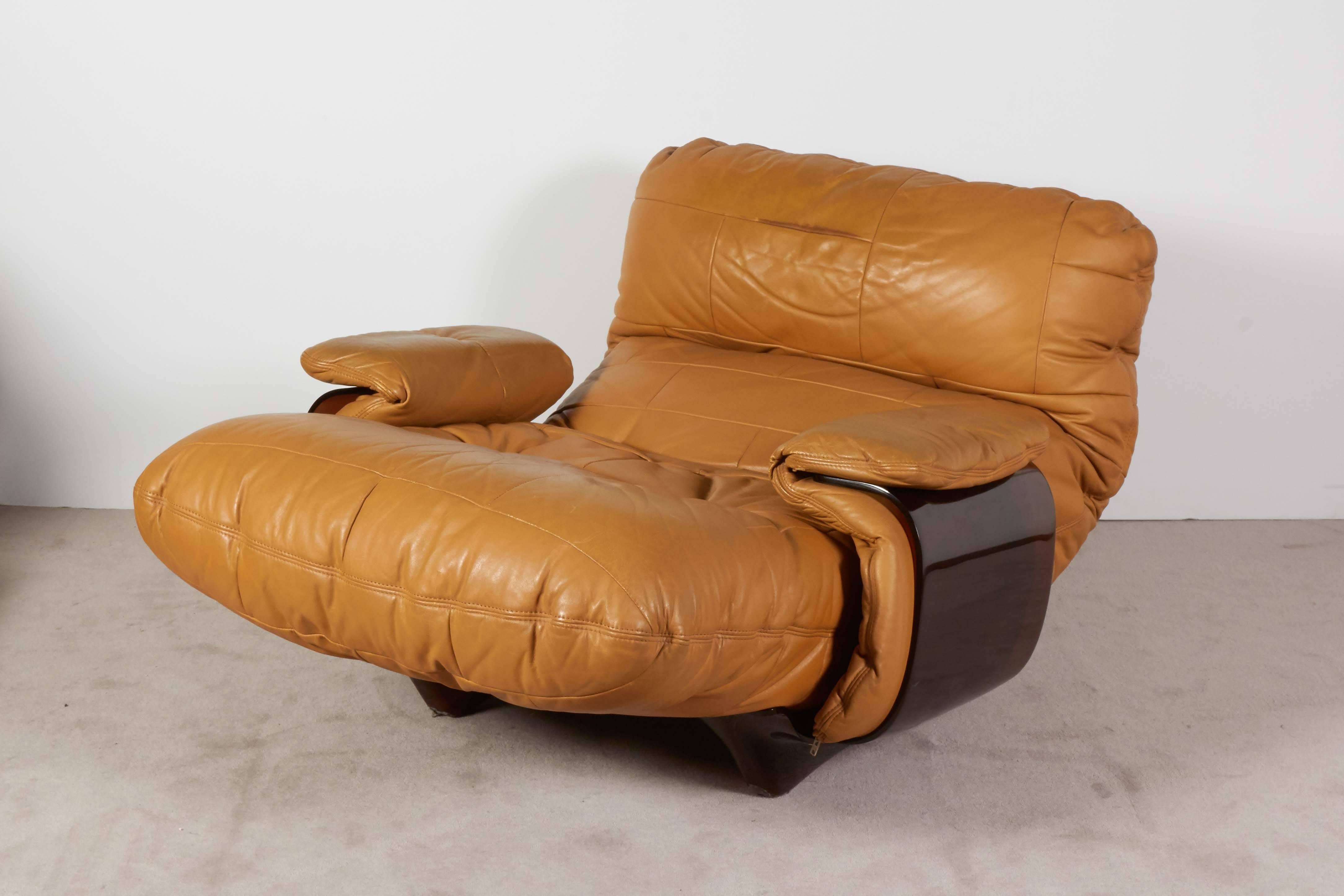 A French, circa 1970s lounge chair and matching ottoman from the 'Marsala' series by Michel Ducaroy, manufactured by Ligne Roset, upholstered in cognac colored leather, against brown plexiglass bases. Markings include original sticker [Roset/Made in