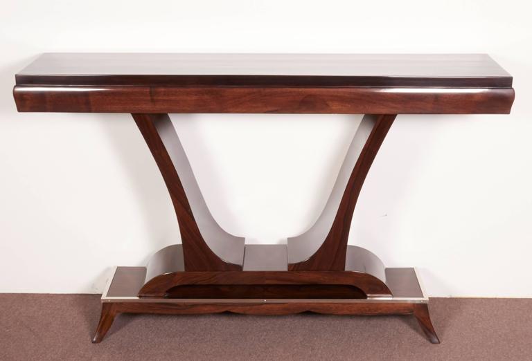 Spectacular pair of French Modern “U” shaped consoles in walnut, mahogany and rosewood high gloss lacquer with nickeled bronze-mounted pediment bases, circa 1925.
This tulip shape is a graceful design element typical of the Deco period.
The console
