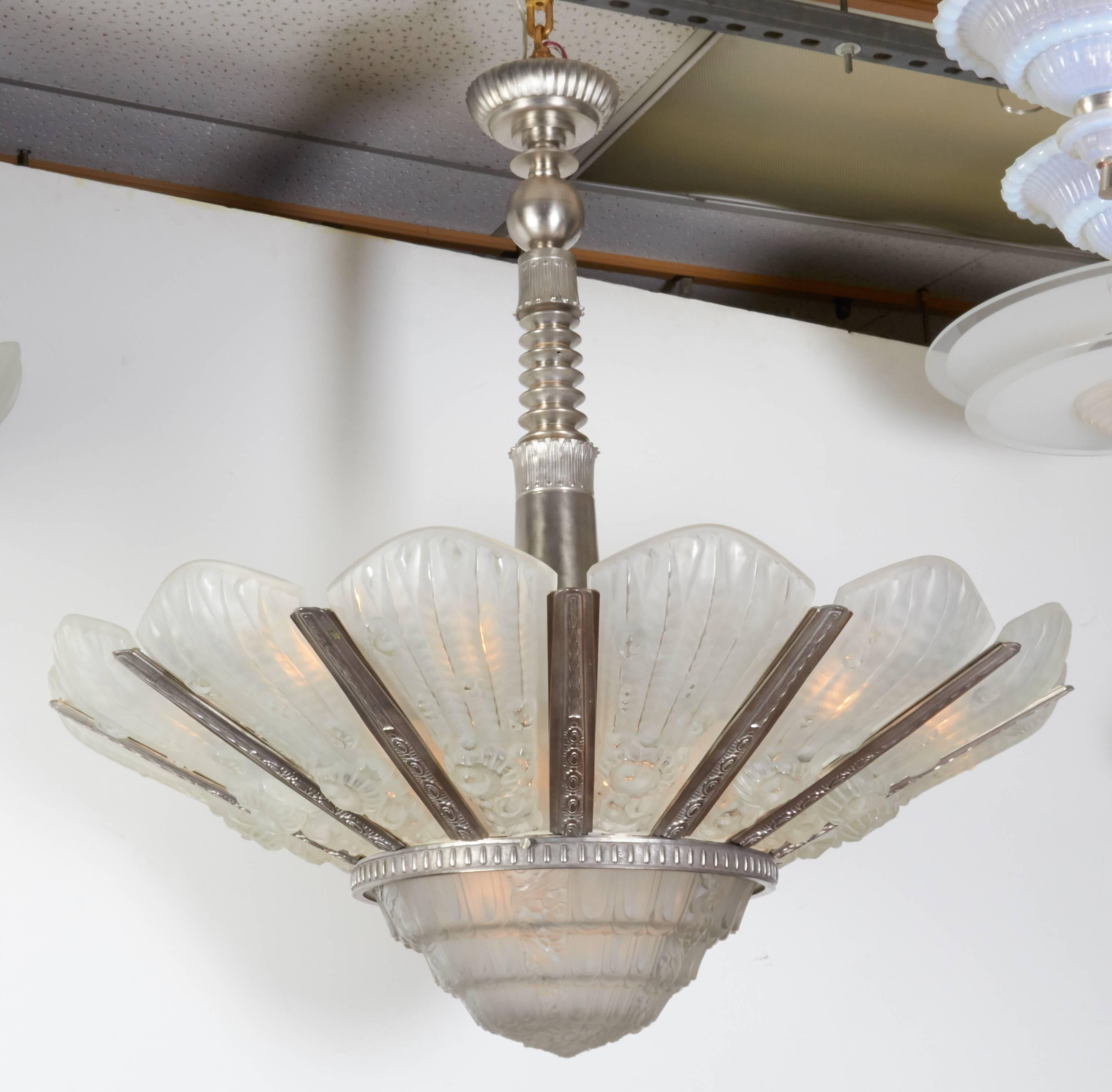 Important and massive French Art Deco sunburst chandelier by Genet et Michon comprising fourteen elongated and heavily molded frosted art glass panels culminating with a deep central coupe, all mounted in a fully detailed and finely machined,