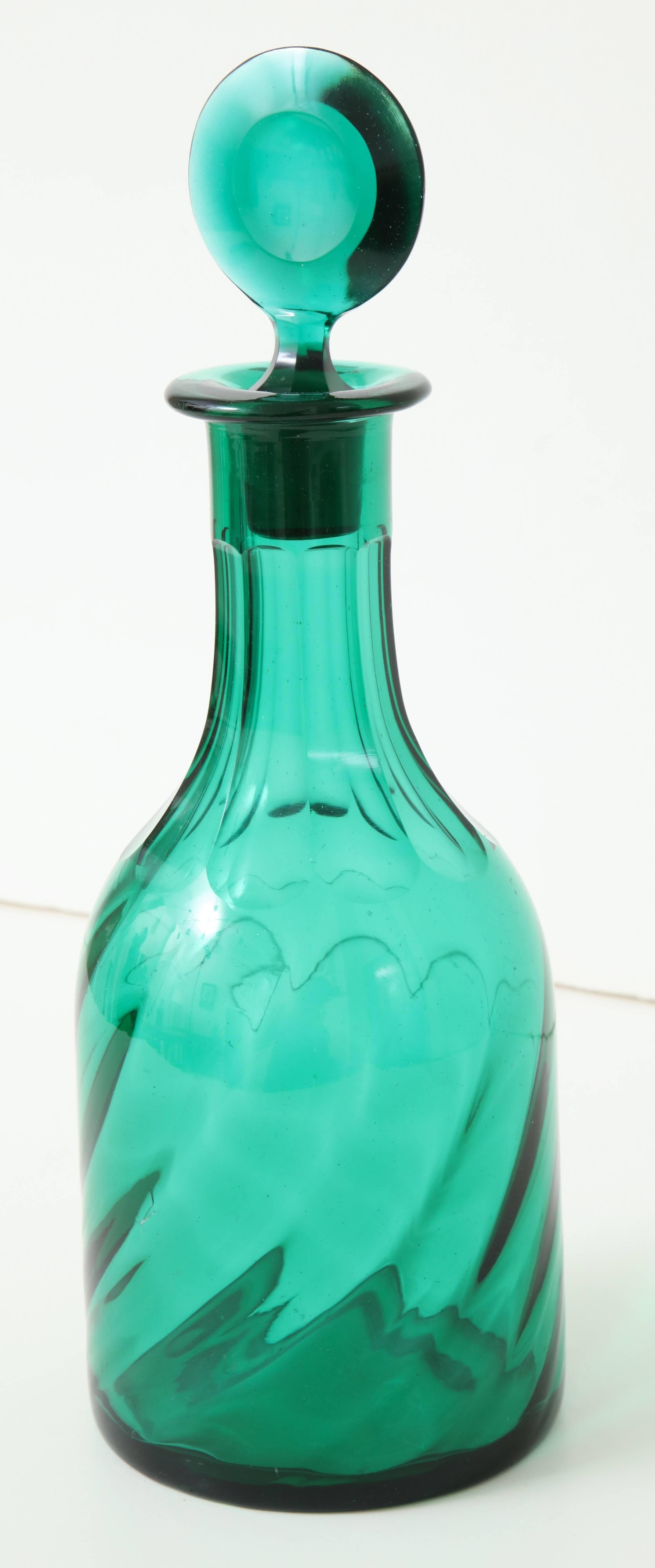 A 19th century English emerald green glass decanter 
with writhen design and faceted stopper.
 