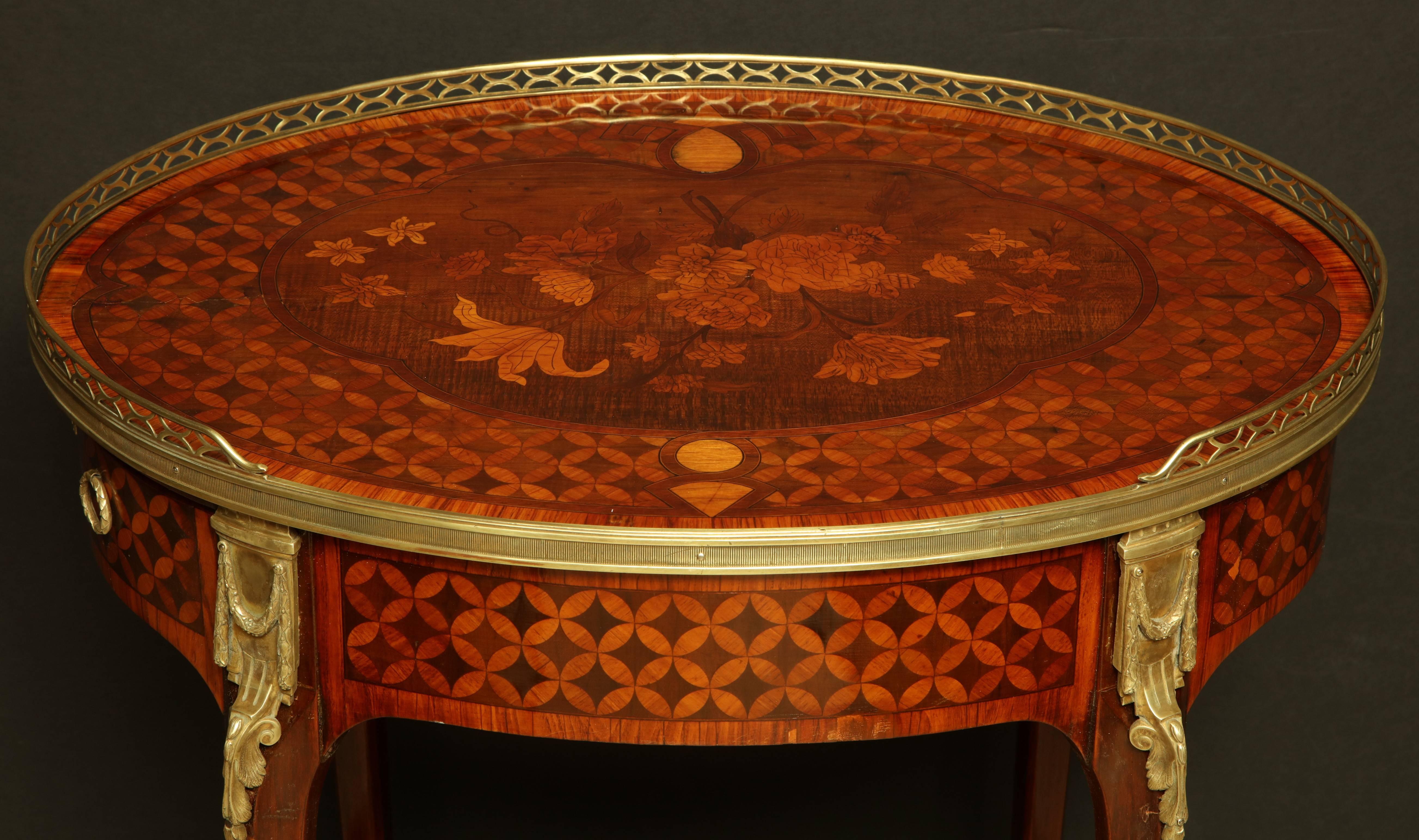 French Louis XV oval marquetry inlaid two-tier side table with pierced bronze gallery and bronze mounts with an inlaid shelf stretcher base.