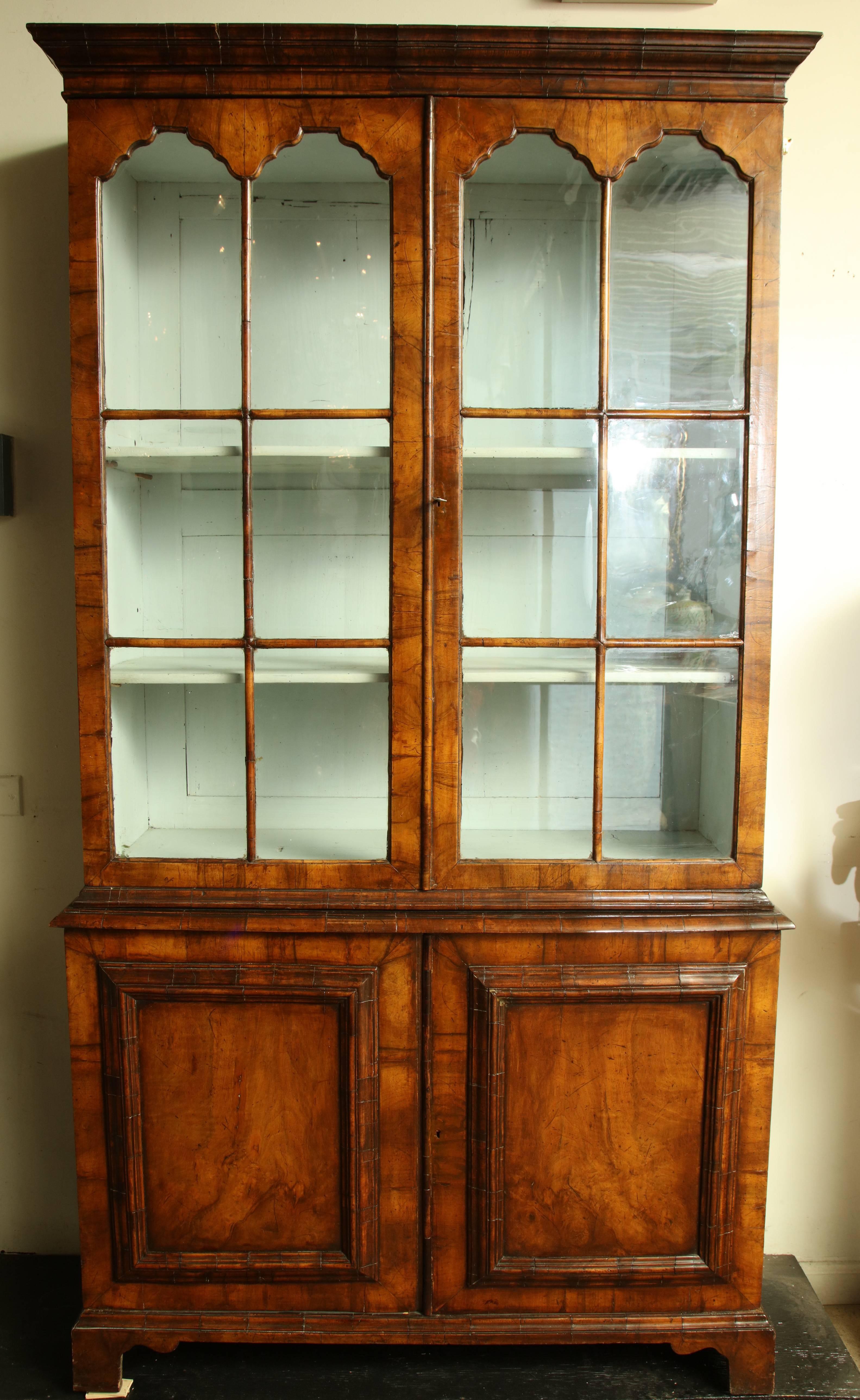 English Queen Anne walnut bookcase with mullion glazed doors above a solid two-door cabinet below and raised on bracket feet.