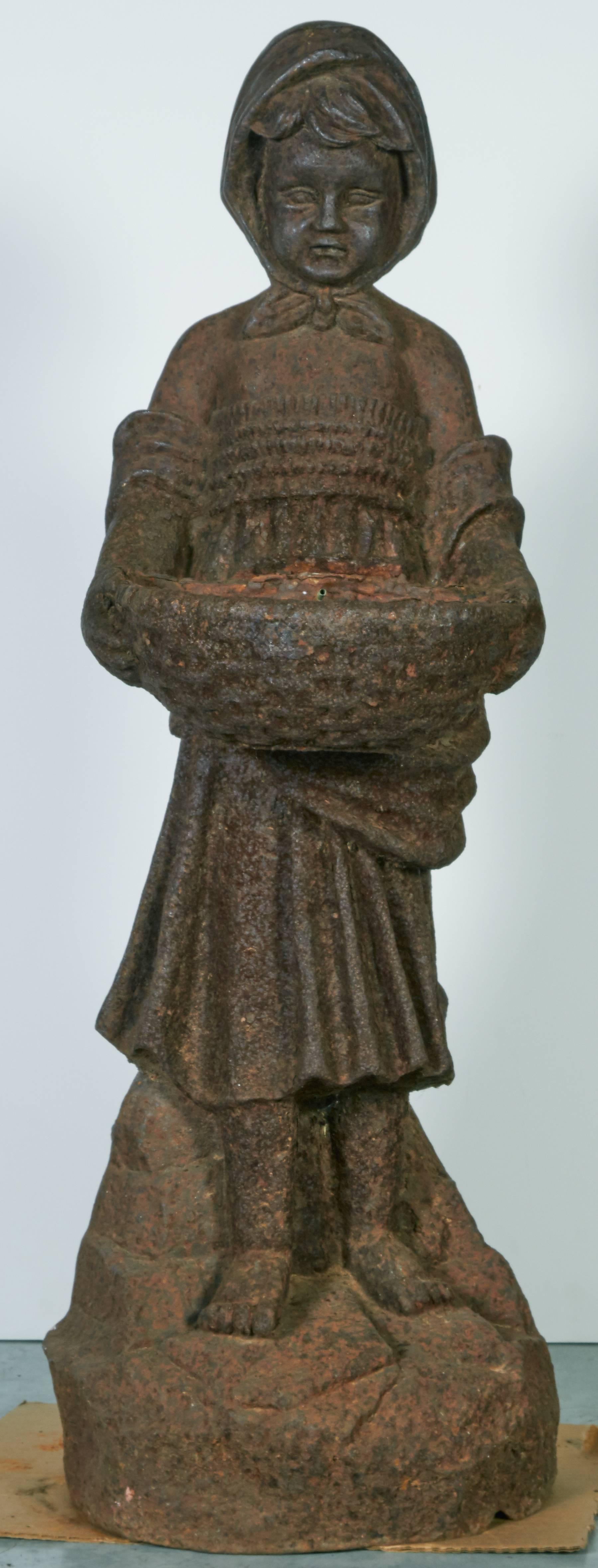 Statue de jardin en fonte française lourde, magnifiquement détaillée, représentant une jeune fille coiffée d'un simple bonnet noué sous le menton et portant un grand bol. Comme la figure masculine qui l'accompagne, son visage est merveilleusement