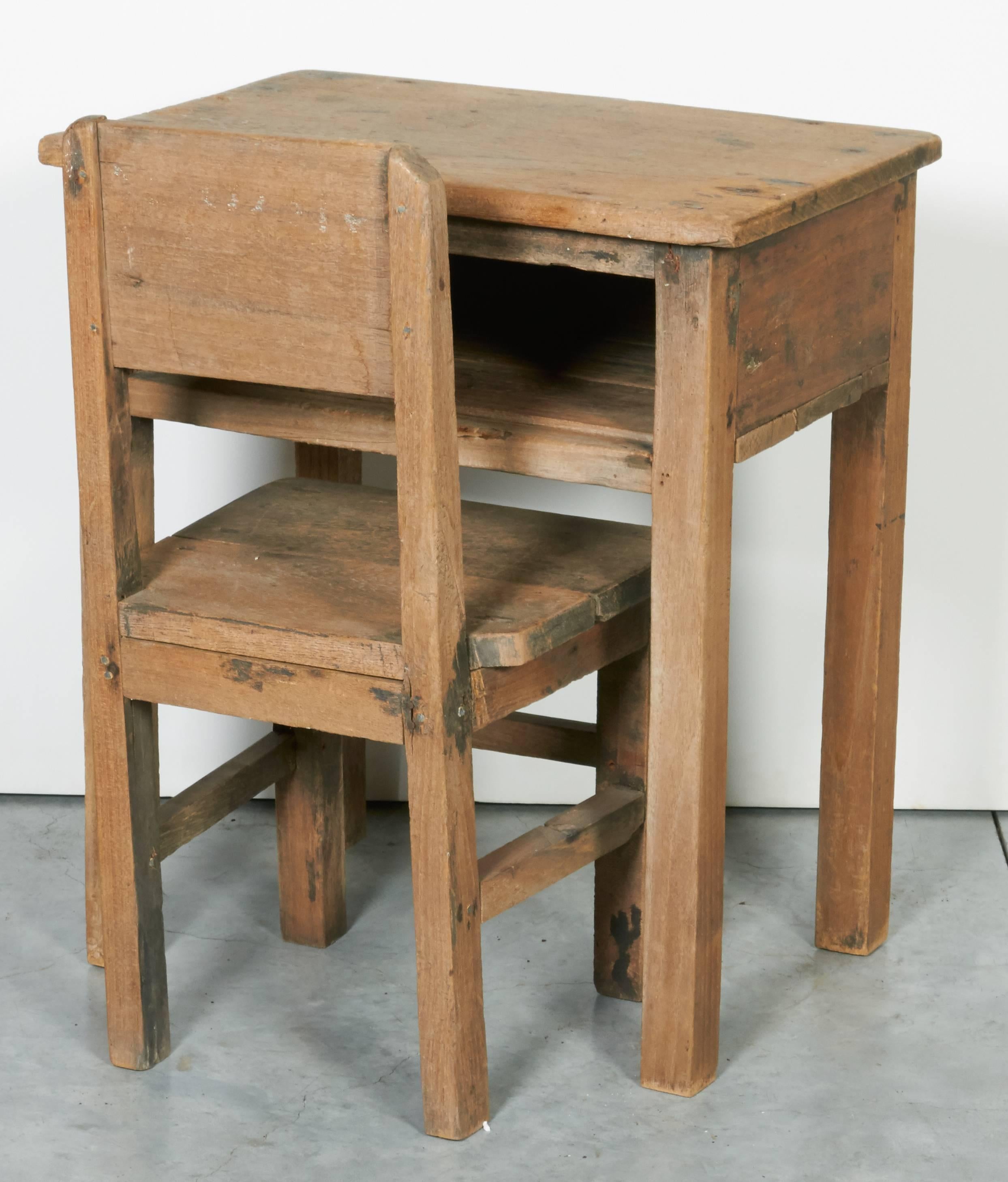 A charming vintage teak child's school desk and chair in a simple, traditional style easily used as a side table or a nightstand, as well it's original use as a child's desk and chair. The old Burmese writing on the back of the desk adds interest