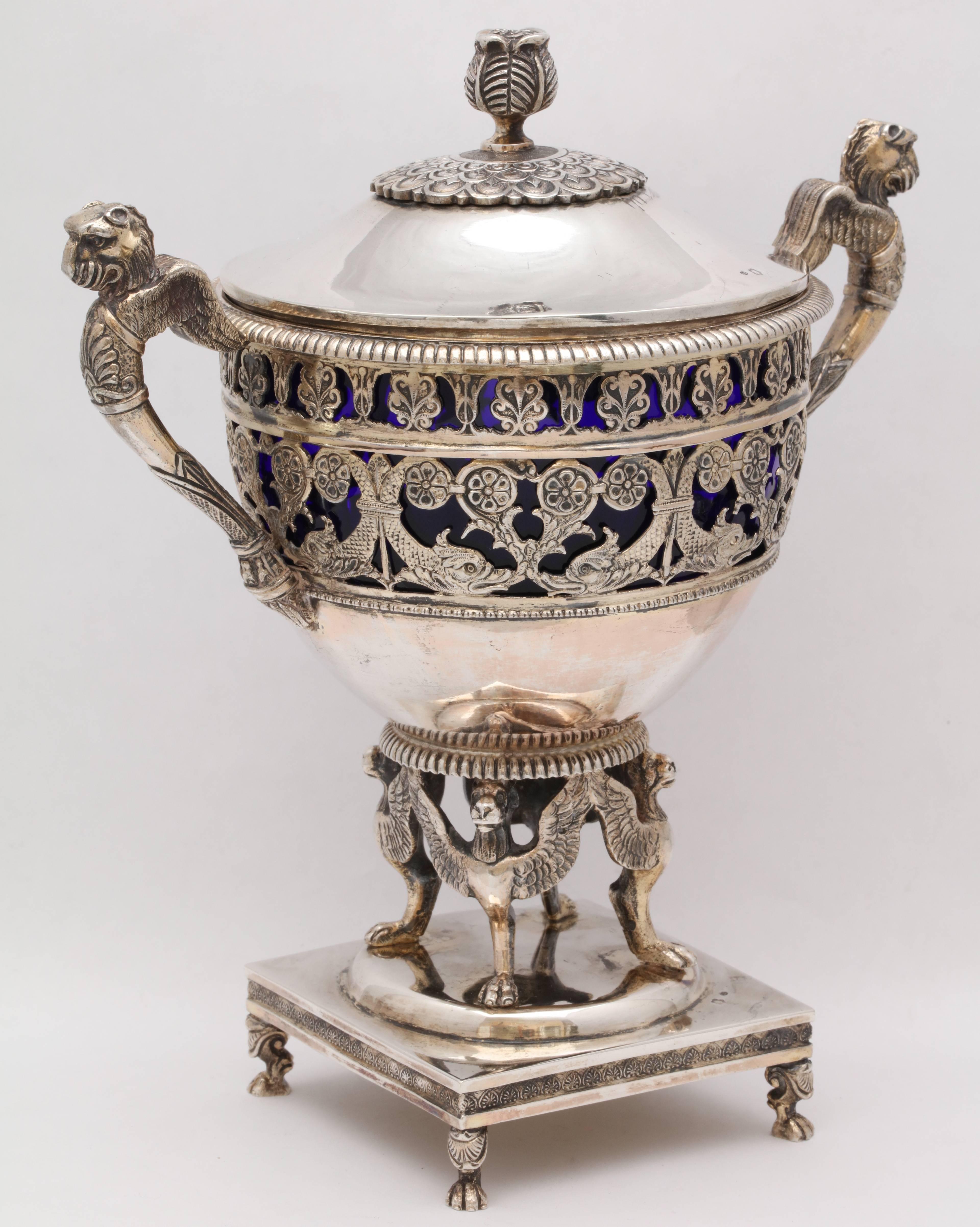 Continental silver gilt (.835), Austro-Hungarian, Neoclassic-style, covered, footed, centerpiece bowl with cobalt blue glass liner,circa 1875.  Arms are winged griffins, as are the footed, winged griffins that hold up the bowl. Piece stands on paw