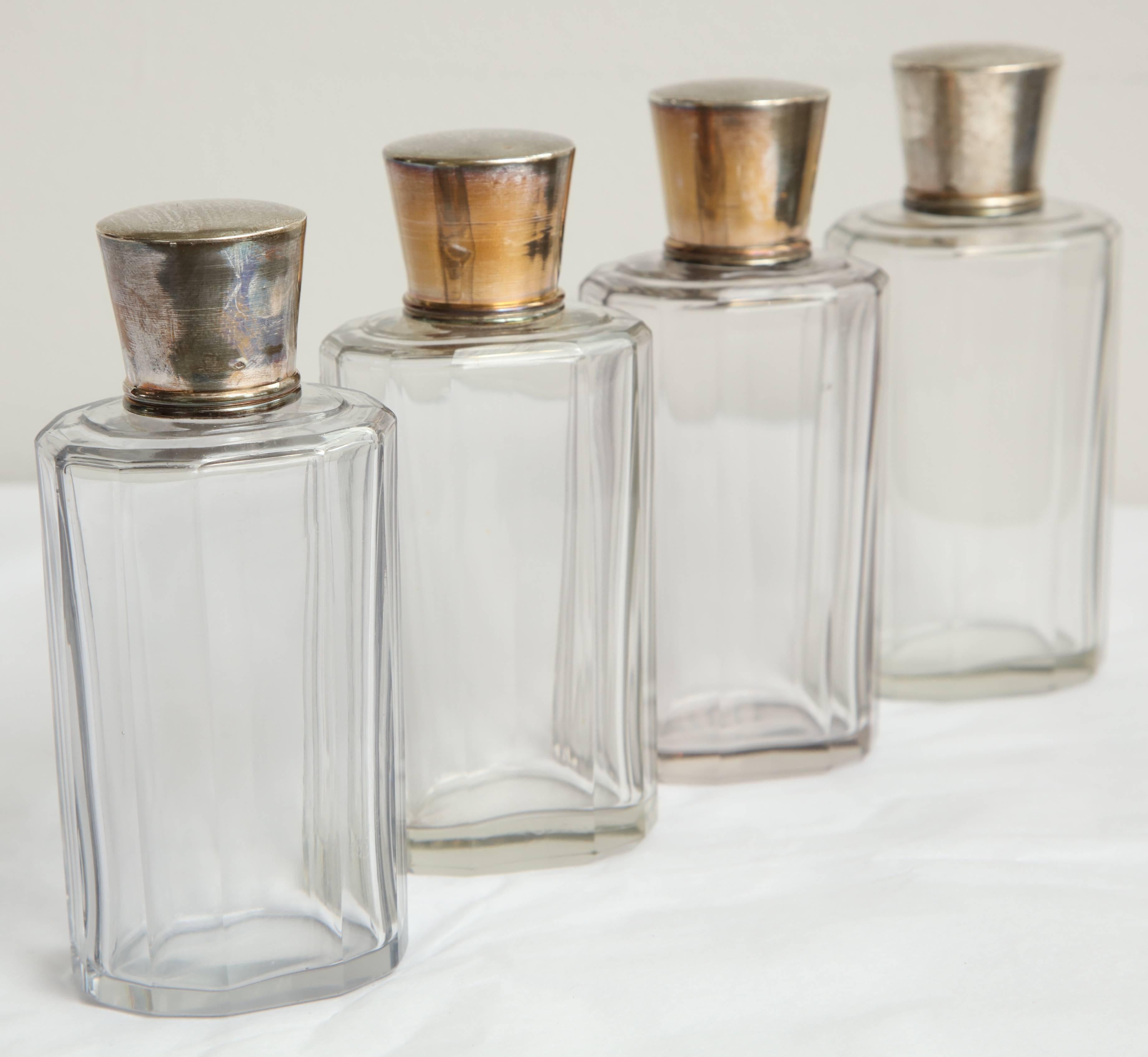 Set of Four toiletry bottles, silver plate tops.
