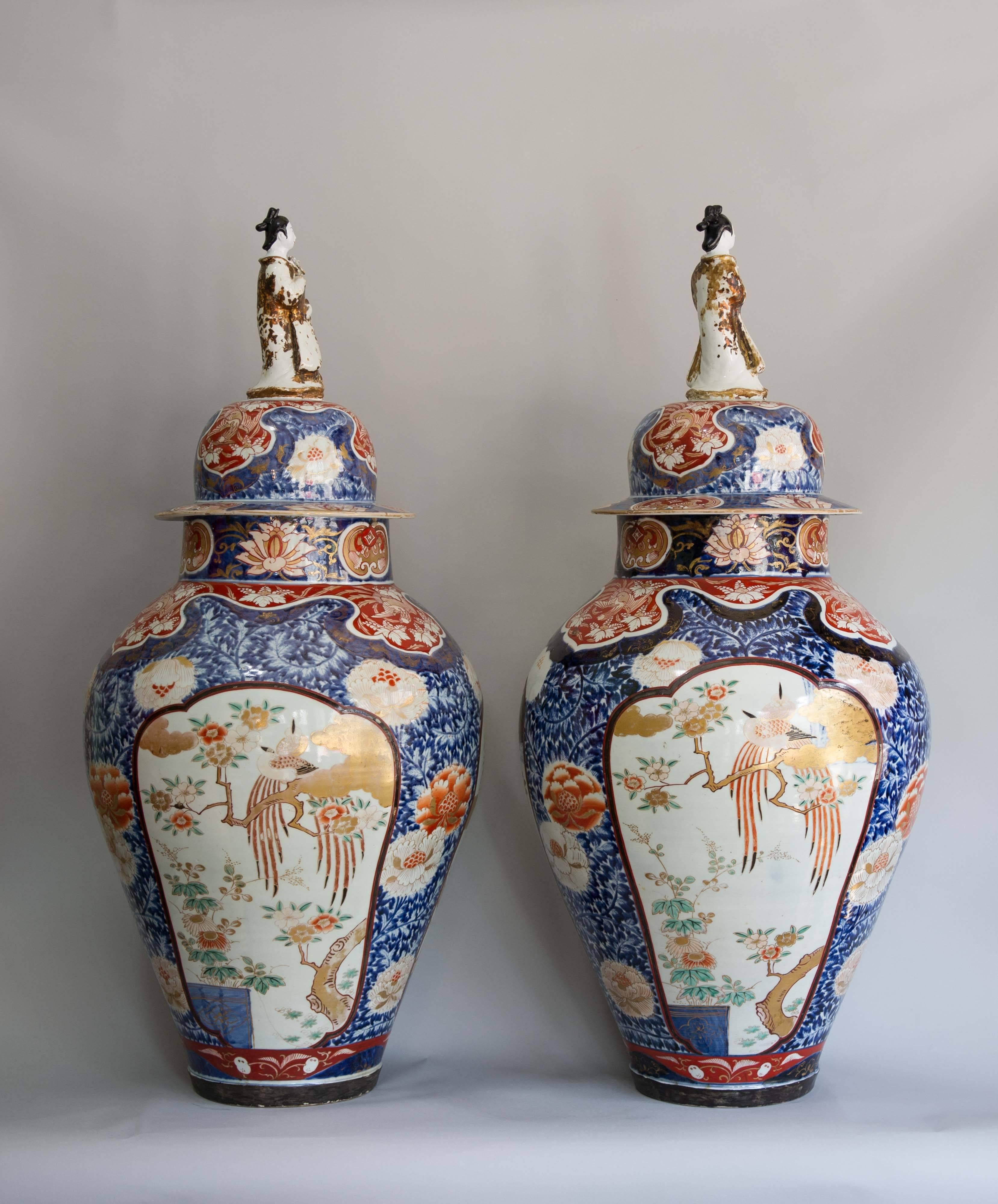 A massive pair of exceptional Japanese Imari vases almost certainly made for a palace. Each is decorated with three beautifully composed landscape panels. Each panel, framed within a cartouche, shows birds of paradise, cherry blossom and other
