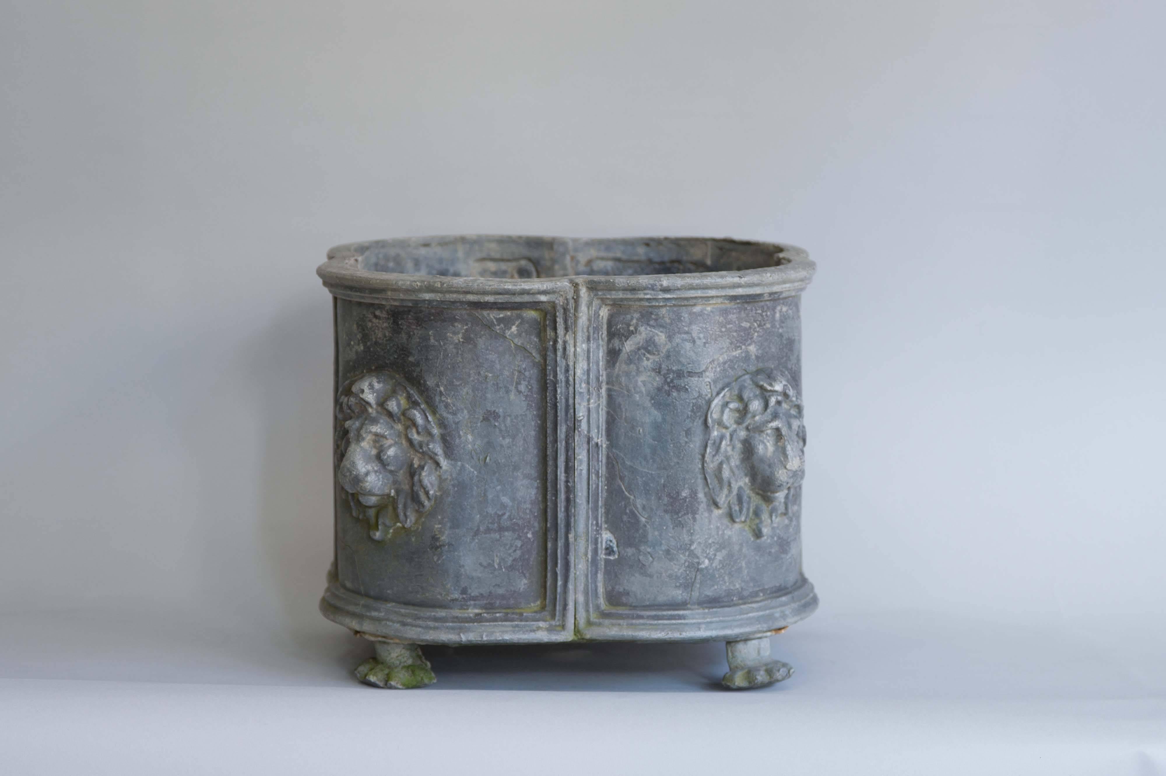 A late 18th century English lead planter. Solid lead in quatrefoil shape with panels showing lion heads and standing on four lion paws. Extremely solid and heavy item to withstand the whims of English weather. The planter has a lovely powder grey