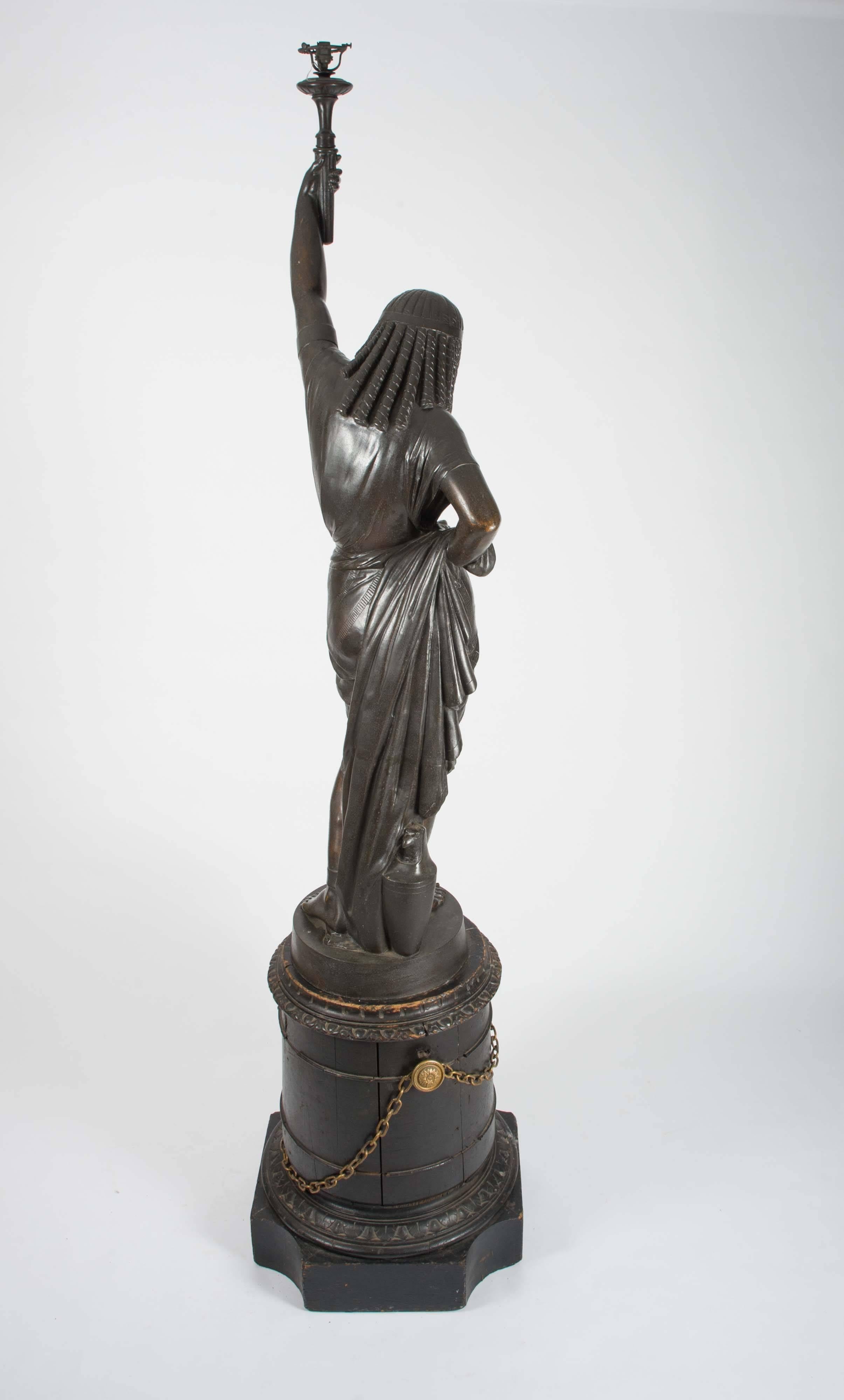 This lifesize French bronze sculpture depicts an Egyptian female holding a light in the form of a torch, which would have originally been a gas light. The sculpture is very detailed and of exceptional quality, standing on a separate ebonized wooden