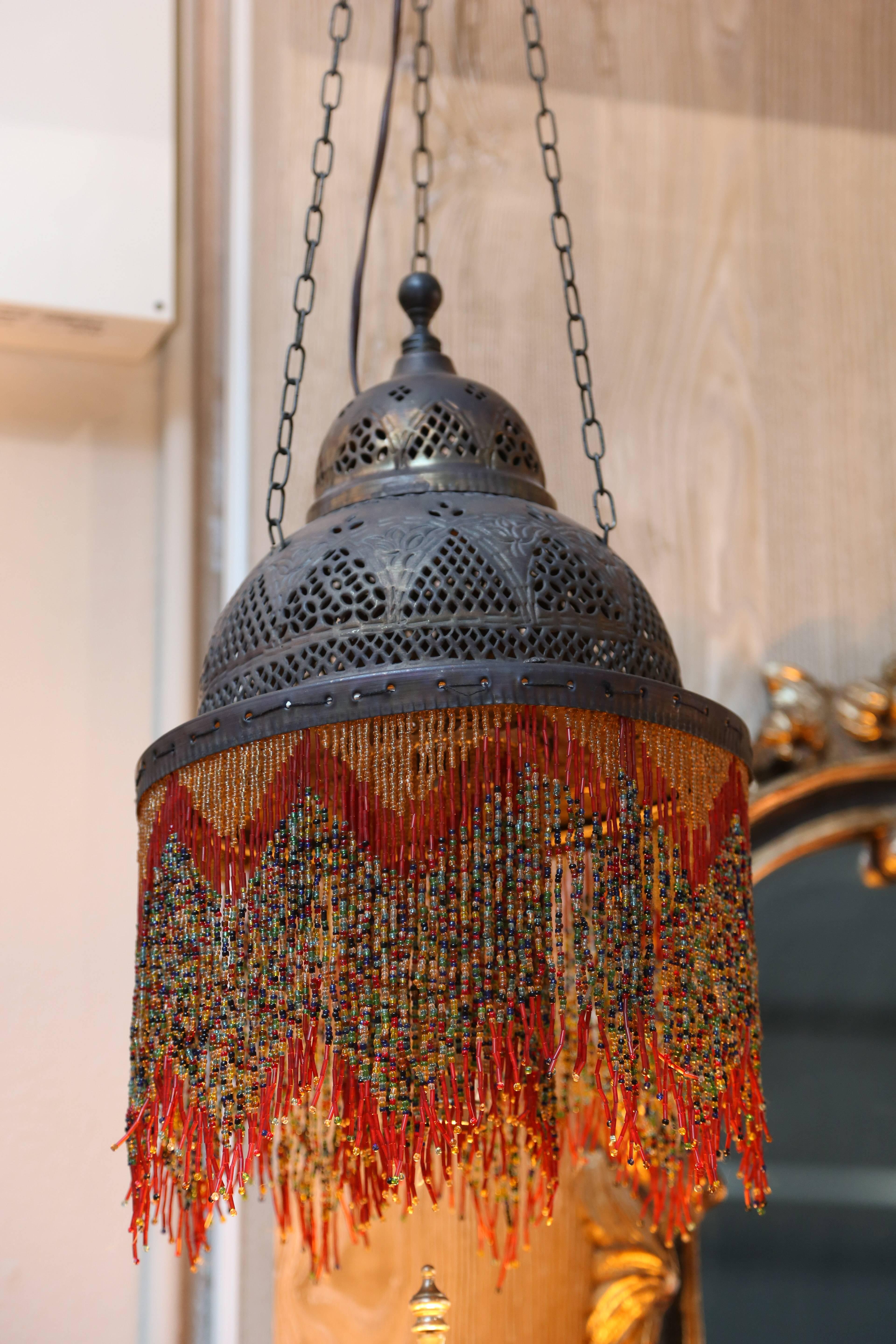 Suspended by three chains, the Classic dome top is elaborately pierced and adorned with beaded fringes both on the rim and surrounding the bulb.