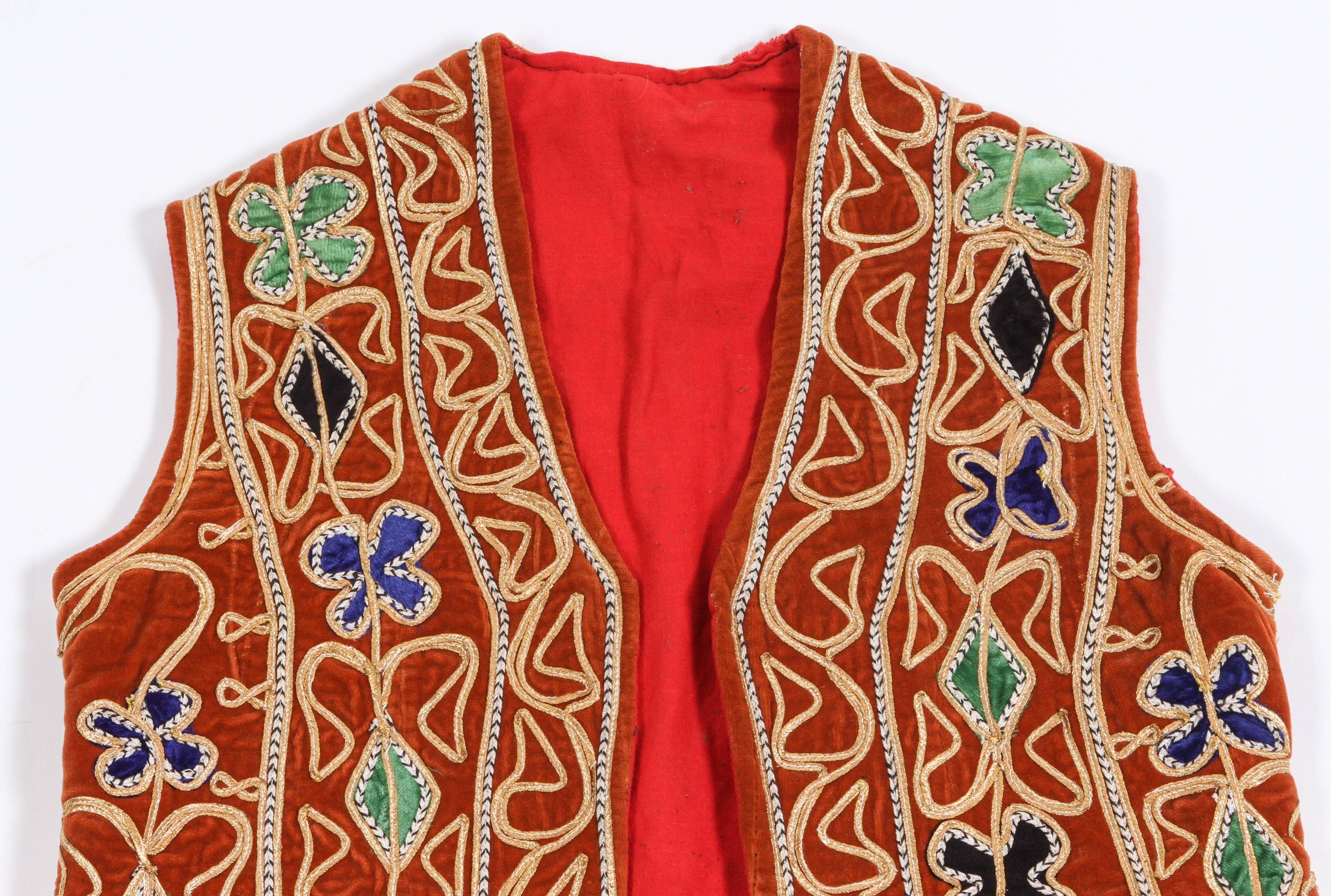 Turkish brightly colored design of geometric patterns against a red ground. Turkish folk costume.
The designs on the open jacket are hand embroidered.
Measures: 29 in, height
18 in. underarm
22in.  wide bottom.