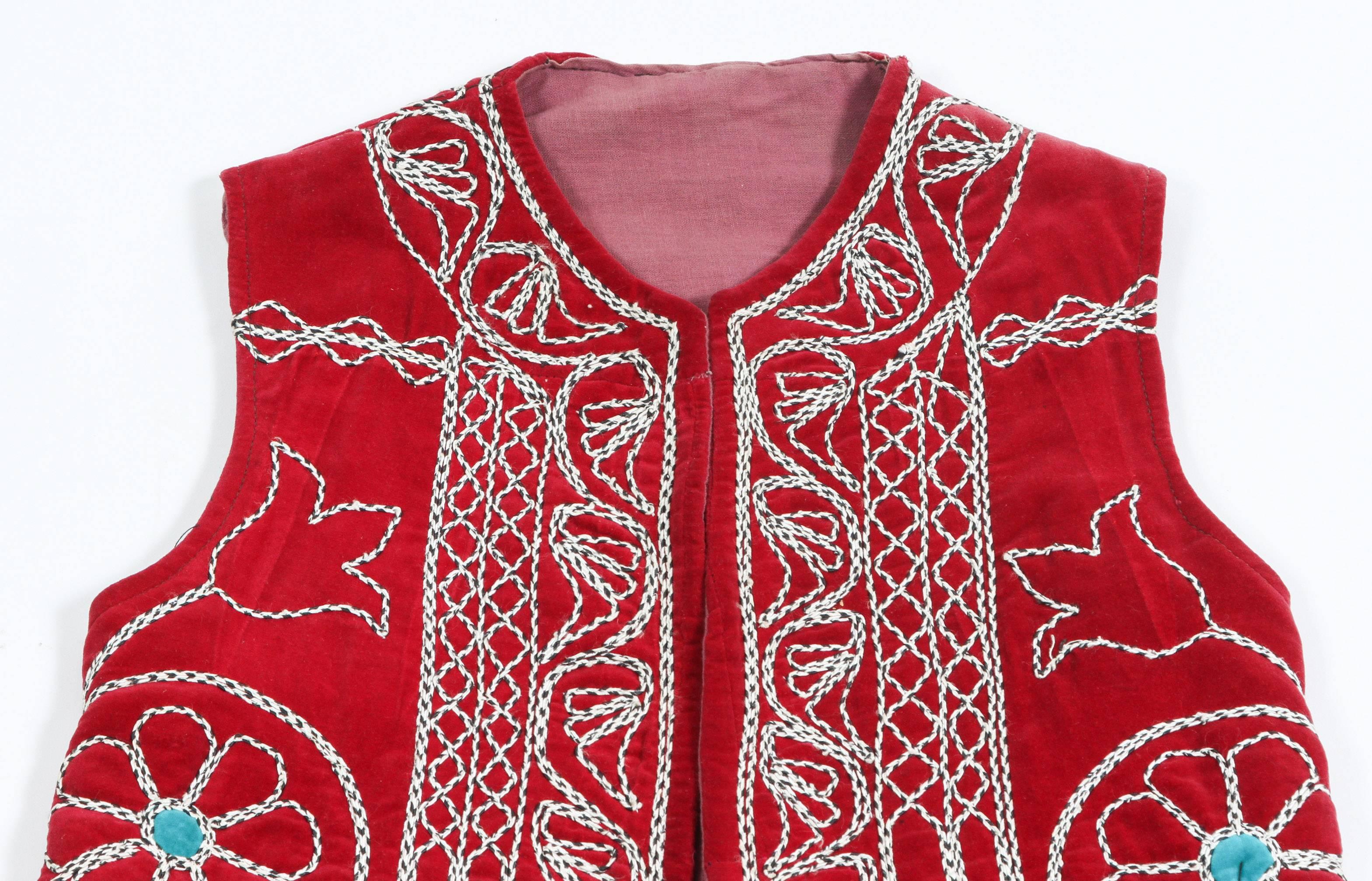 Elegant Turkish long vest brightly colored design of geometric patterns against a red ground.
Part of Turkish folk ceremonial traditional costume.
The designs on the open jacket are embroidered with white threads, flowers and elaborate geometric