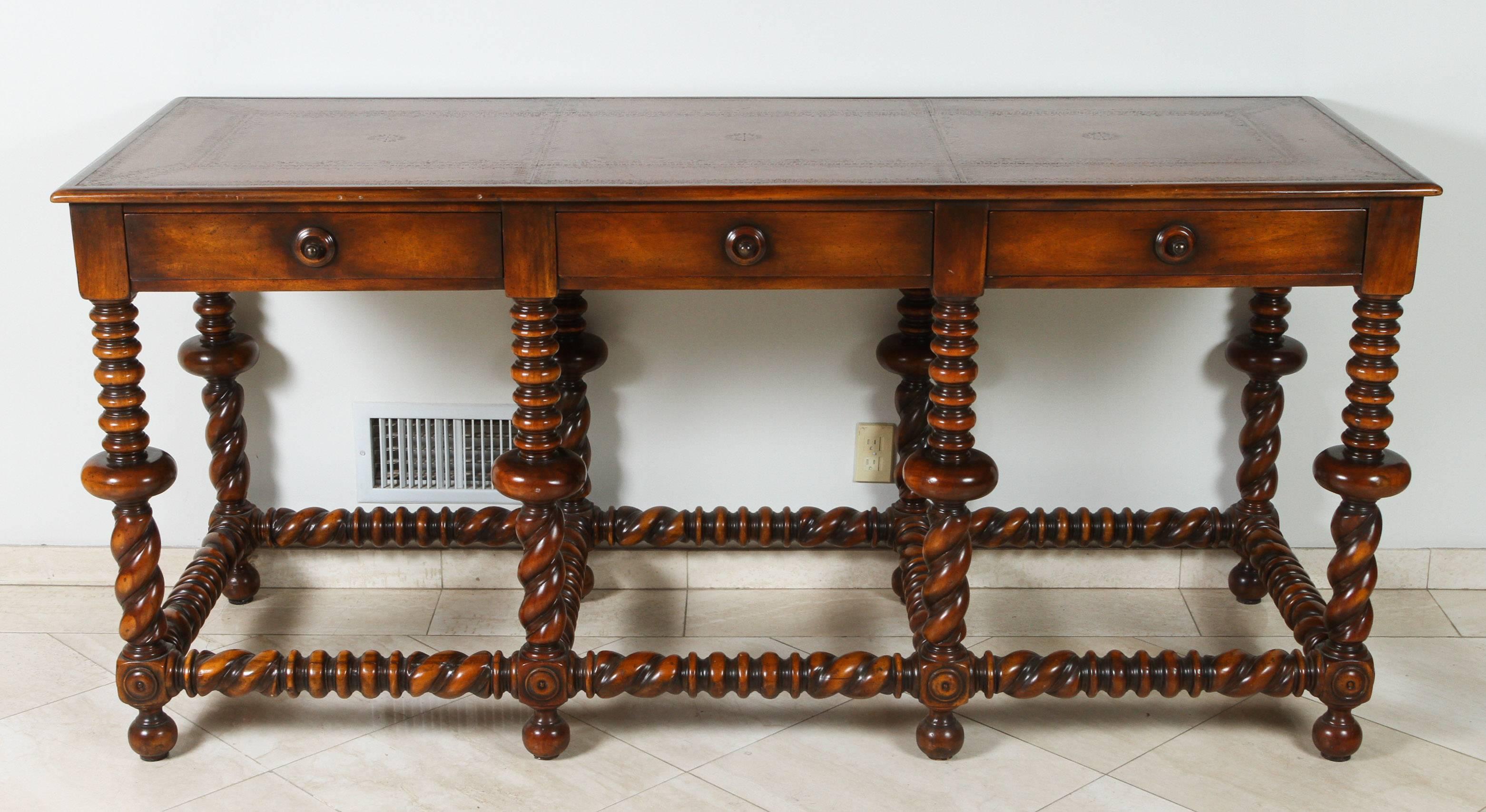 Monumental Portuguese style wooden console table with leather top.
Portuguese style polished and carved wood table with circular and bulbous designed twisted legs and stretcher, top is leather covered with beveled edge with three deep set drawers