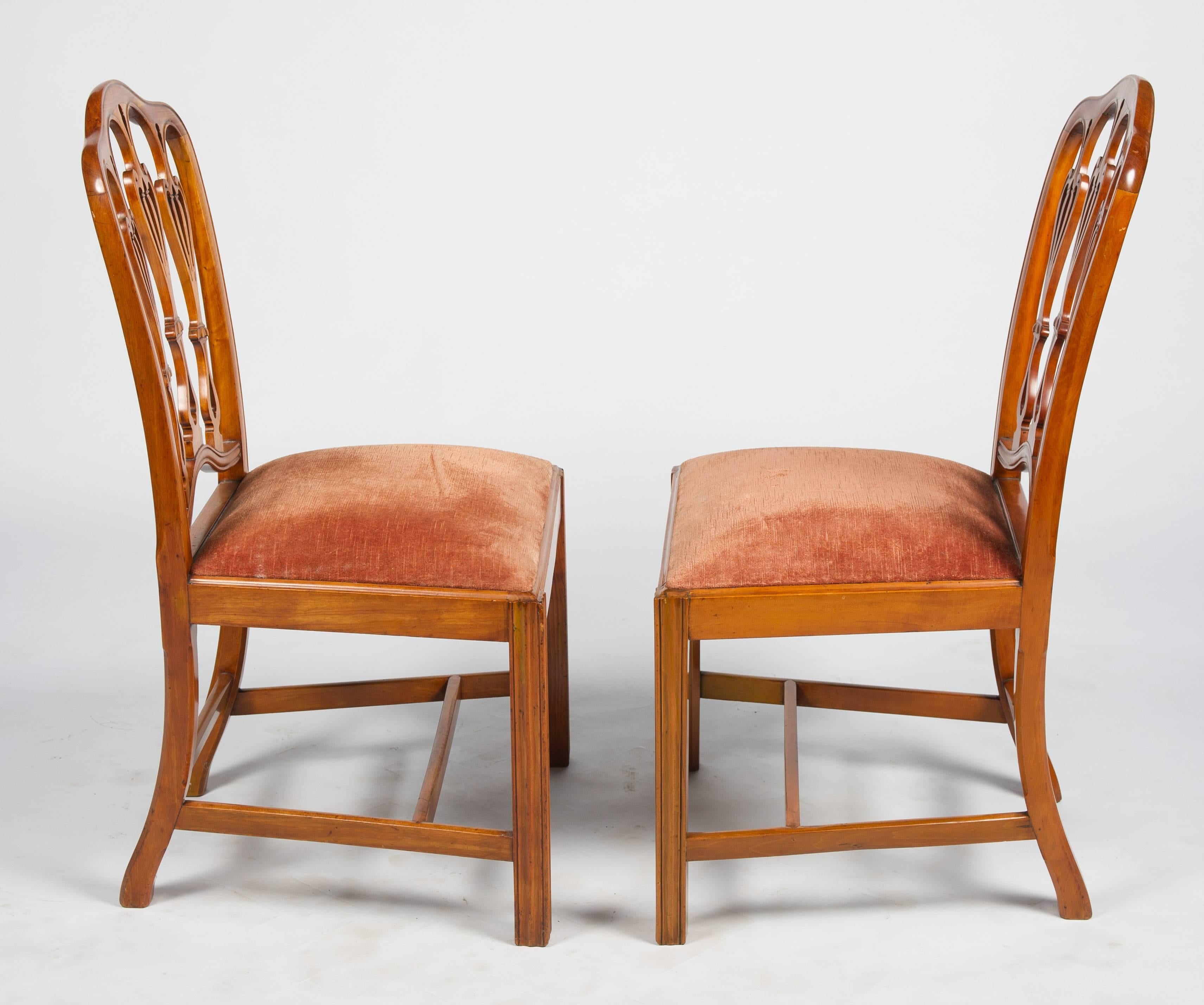 A rare pair of Hepplewhite George II period satinwood side chairs. The backs each with three carved and fretted urn like splats. Drop in seats and raised square section moulded legs and united by H stretchers.