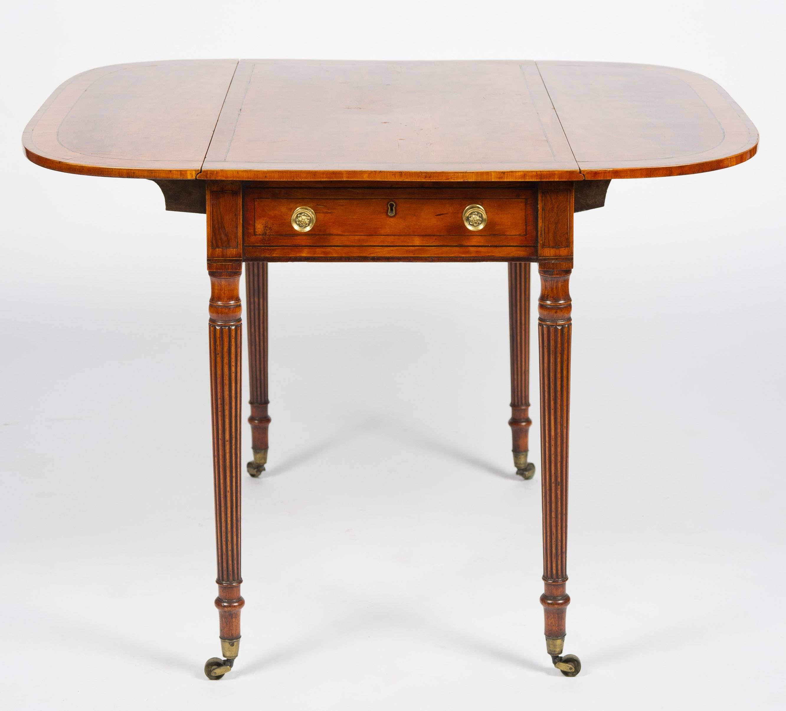 A very good quality early 19th century satinwood pembroke table, in the manner of 'Gillows'. The top being crossbanded, a single frieze drawer with brass handles, raised on turned tapering reeded legs, terminating in the original Brass castors.