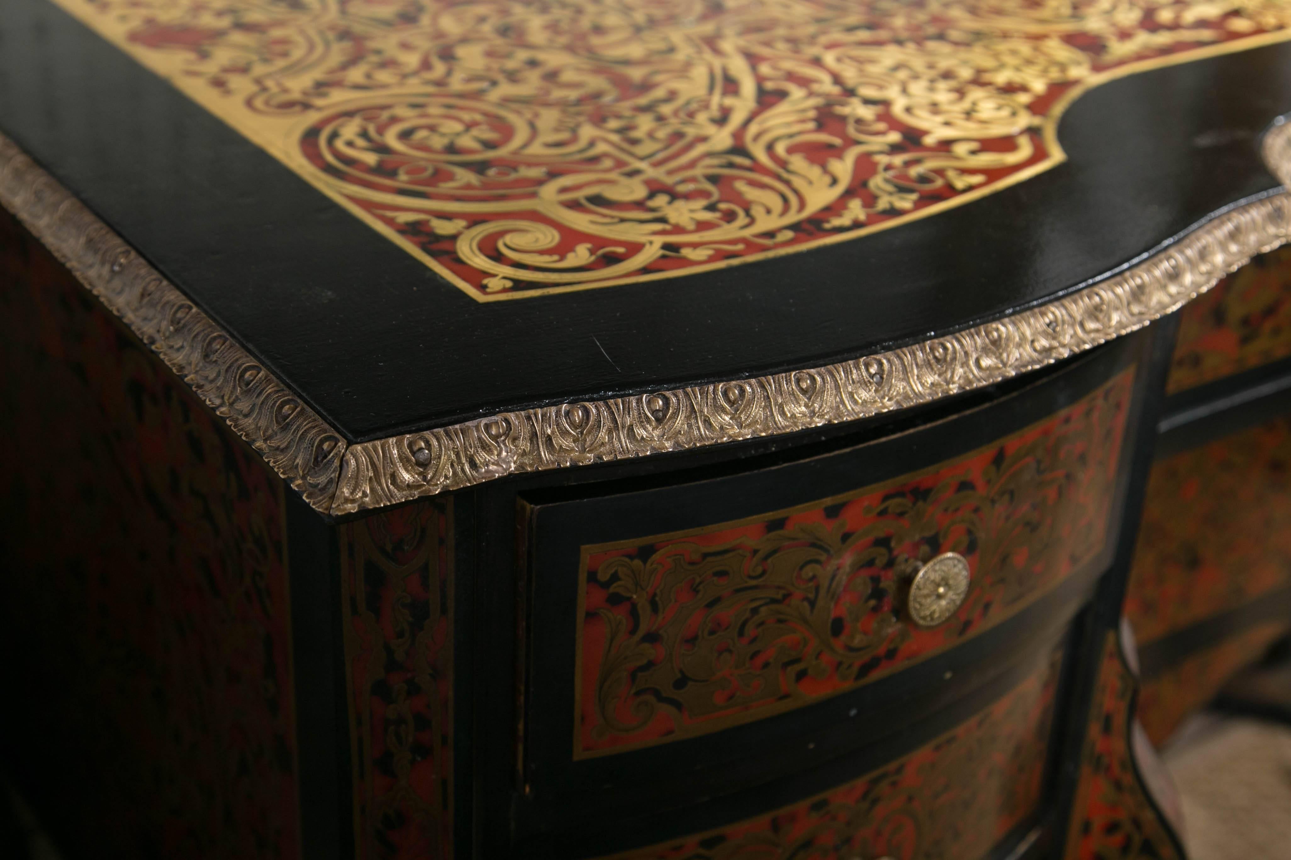 In the Louis XIV style, this desk has faux tortoise shell and brass inlays.
X form stretchers connect the front and back legs below each bank of drawers. There are three drawers on each side, a center drawer and a drop down front cabinet in the