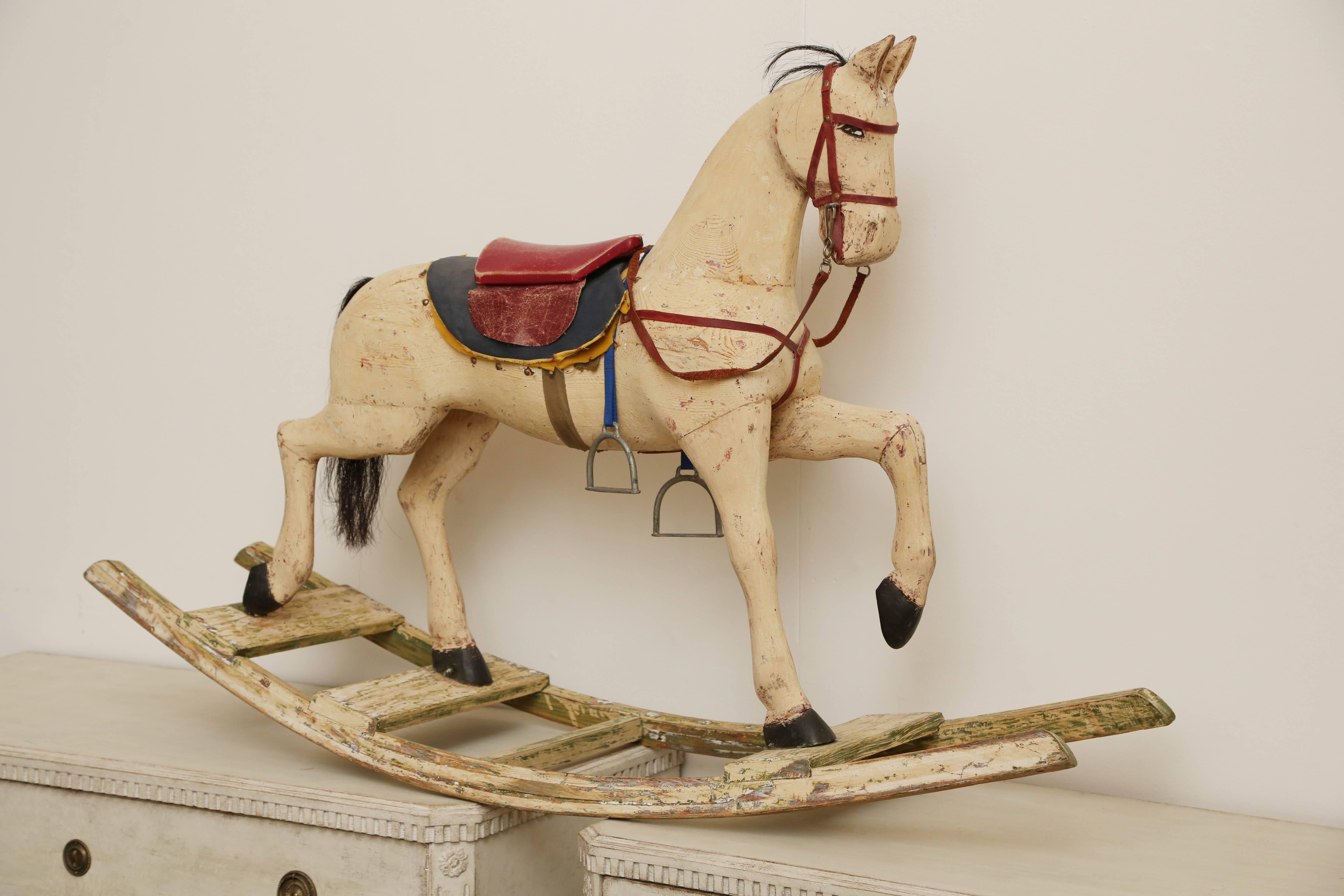 This antique Swedish rocking horse from the south of Sweden comes complete with saddle, reigns and metal horse shoes and stirrups. The tail and mane are made of real horse hair. Sturdy construction. The paint has been stripped down to it's original