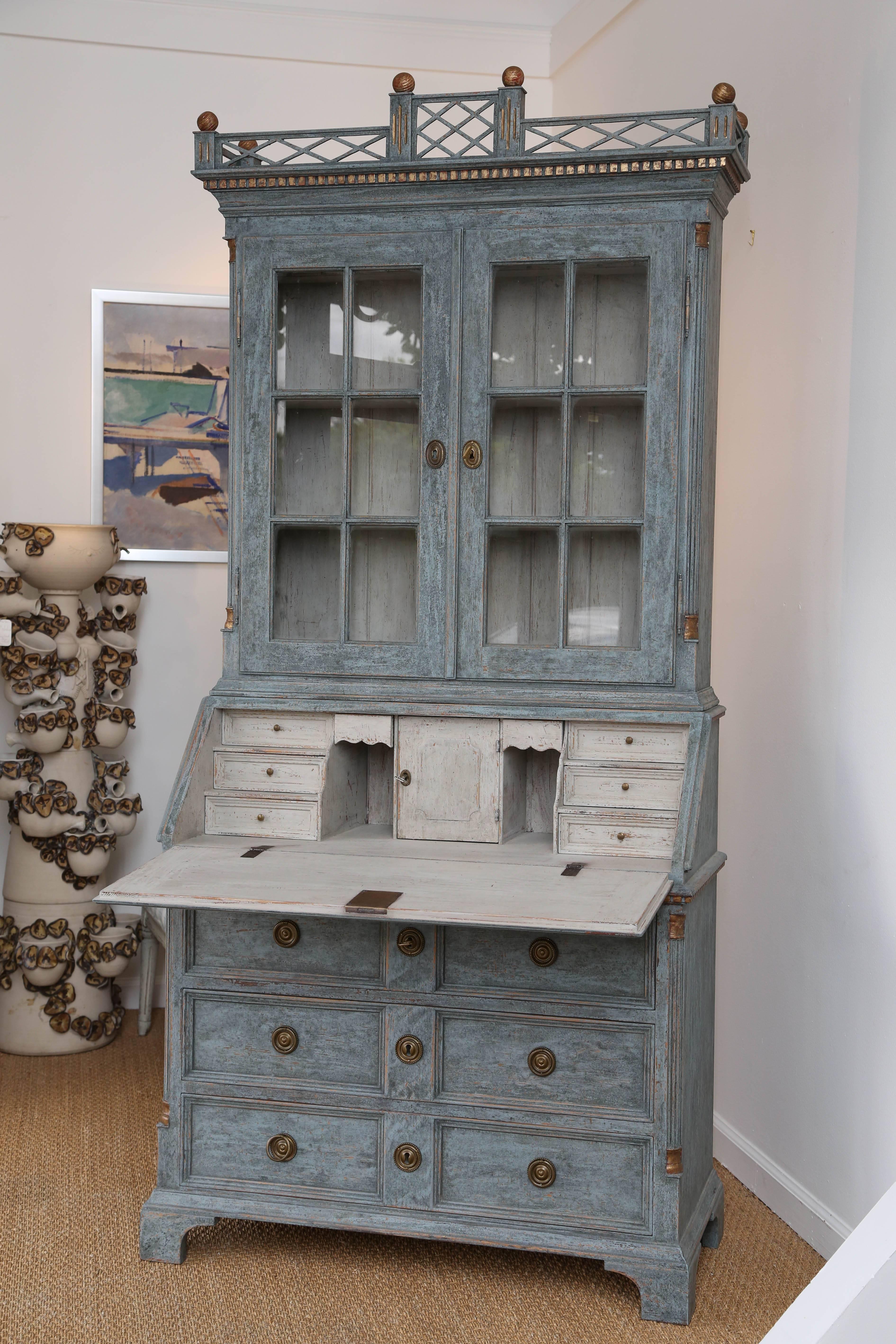 Antique Swedish Gustavian style painted secretary-bookcase mid-19th century
Painted in Swedish blue distressed with gold leaf accents.
Top section has glass panel doors and two shelves, one bottom shelf, has a
fabulous canopy of fret work and