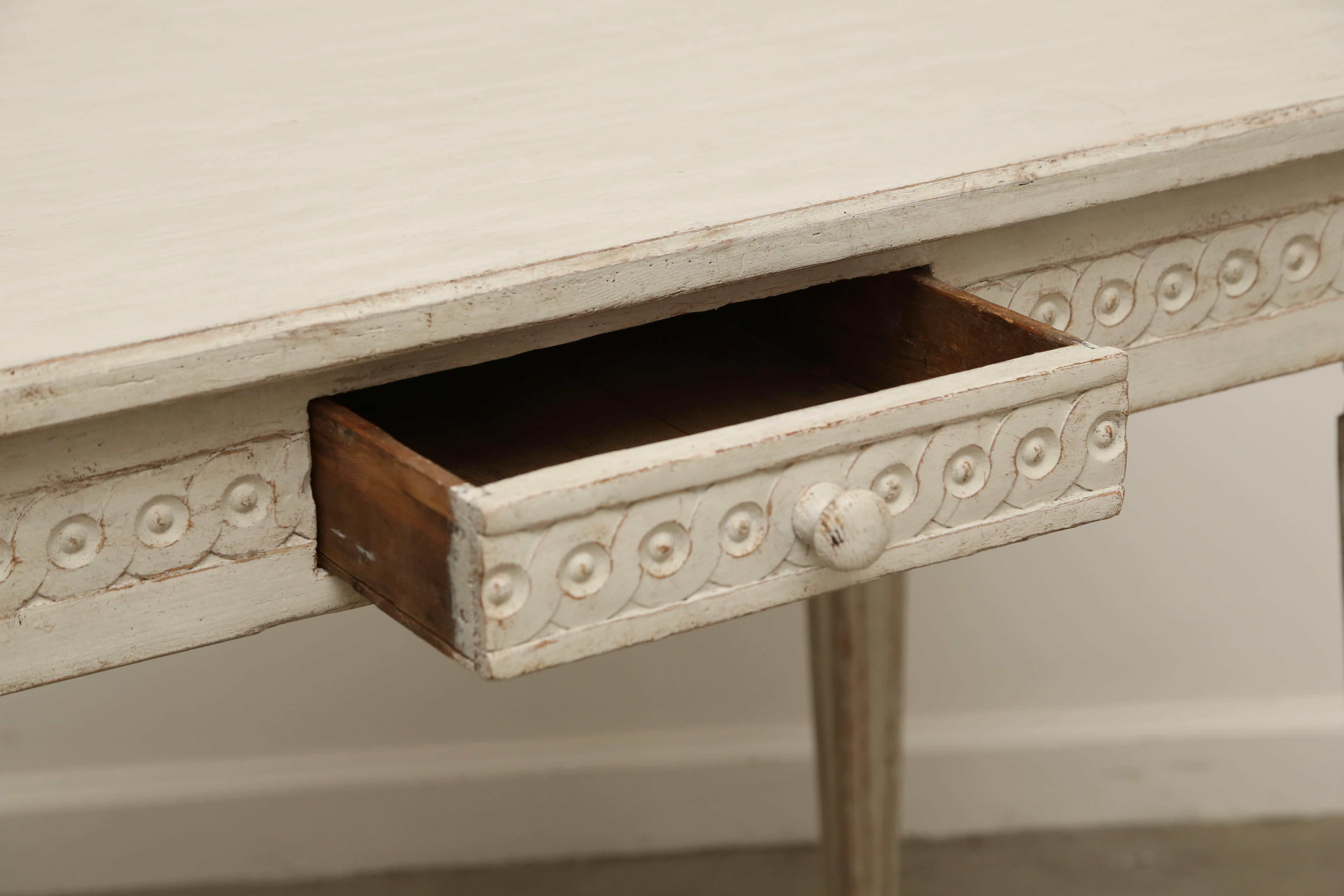 Antique Swedish painted Gustavian Style console table distressed painted in traditional Gustavian white. There is an interlocking circular border around the
apron and on the front of the drawer, carved rosettes on corners,tapered legs.
This console