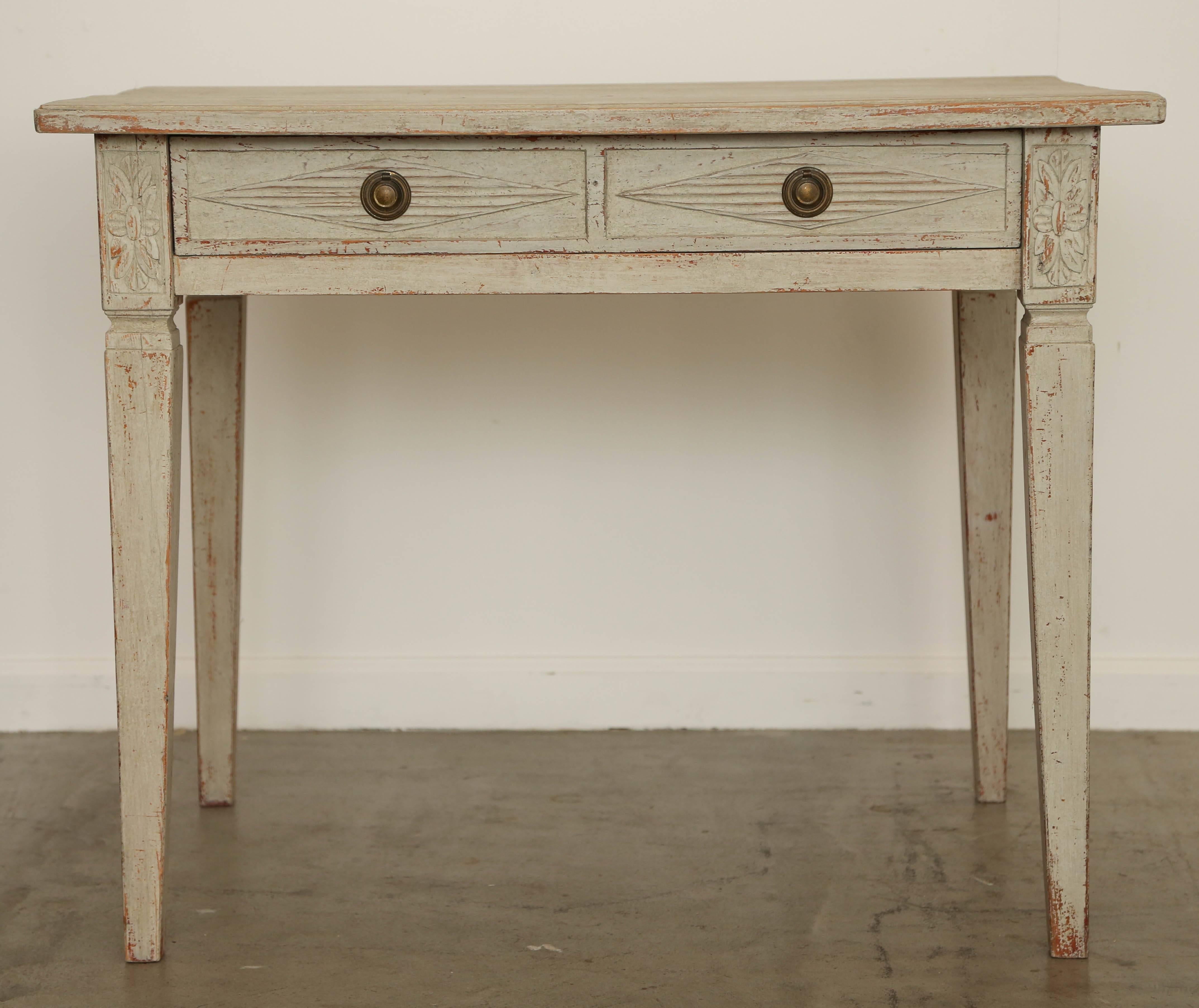 Antique Swedish Gustavian style painted writing desk with one drawer, mid-19th century simple top with small ODedge, one large drawer with two diamond receded shaped designs with brass pulls, carved rosettes at top of the legs,
tapered legs. Painted