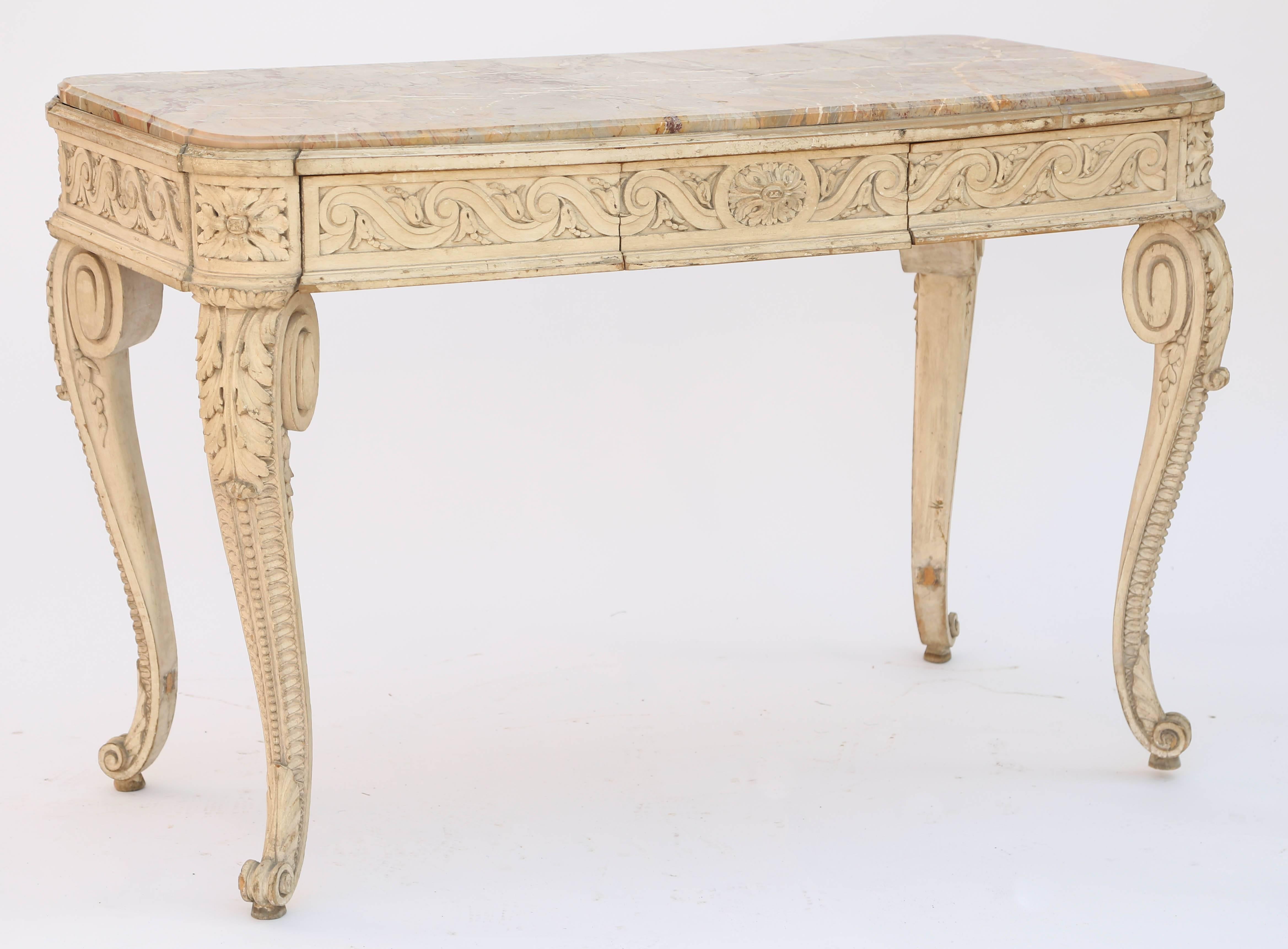 Centre table, or console, having a molded top of marble with rounded corners, inset into conforming, painted table base, showing natural wear, its apron carved with evolute scroll, flanking a single frieze drawer, raised on out-turned, scrolling