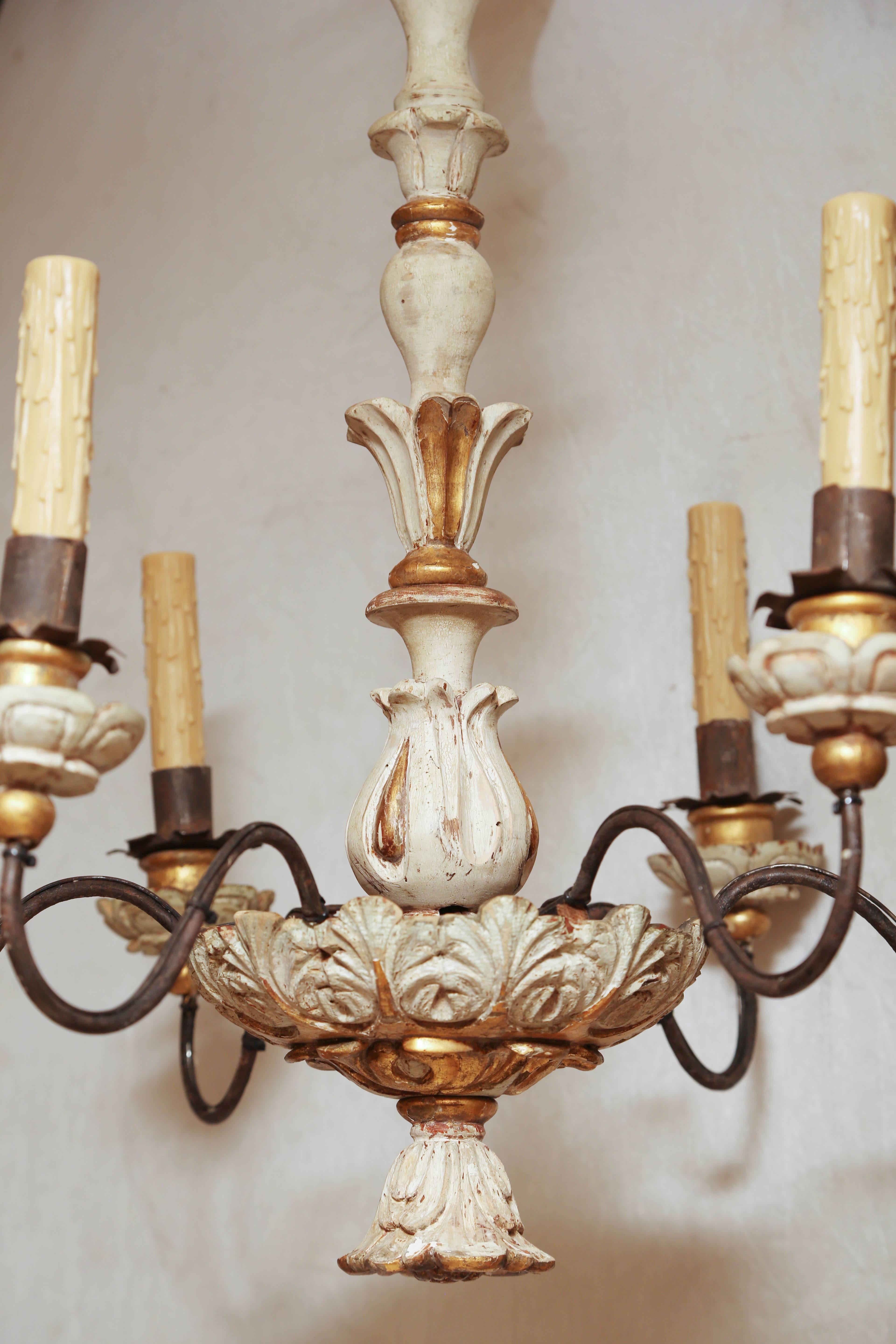Chandelier, having a painted and parcel-gilt finish, its foliate-carved and turned centre column, surmounting an elaborately carved bowl, finished by a bell-form rosette finial, with six iron S-scroll candle arms extending from the centre, ending in