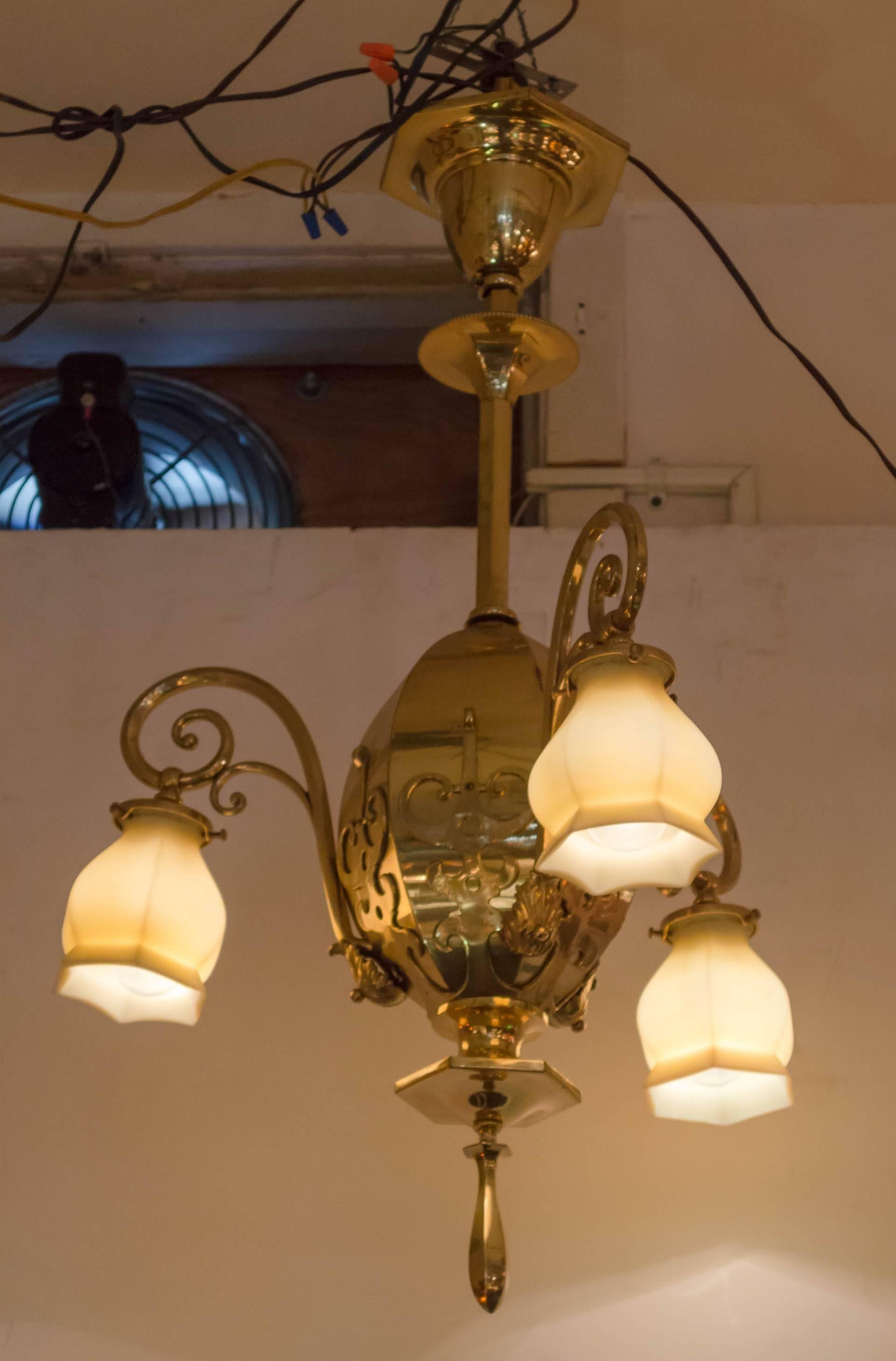 This very handsome chandelier is perfect for an entryway, or any other room in the home. The body is polished brass with unusual applied casting. The glass shades are some of our favorite options. Vaseline glass, or sometimes called custard glass