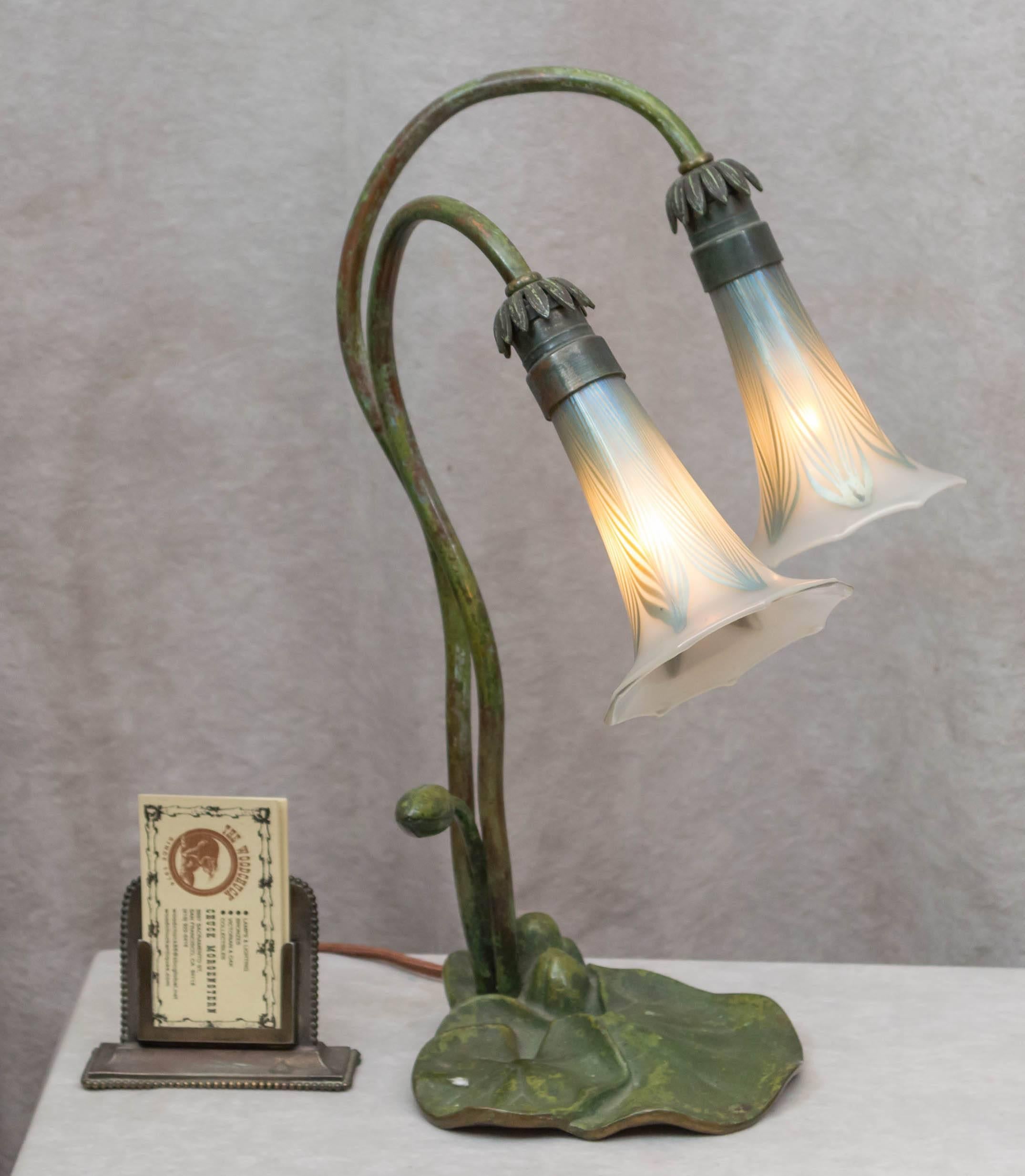 A very good example of the Art Nouveau period is what we have here. The factory green patinated base is enhanced with two original pulled feather style glass shades. Tiffany did a similar example during the same period. We believe this was very