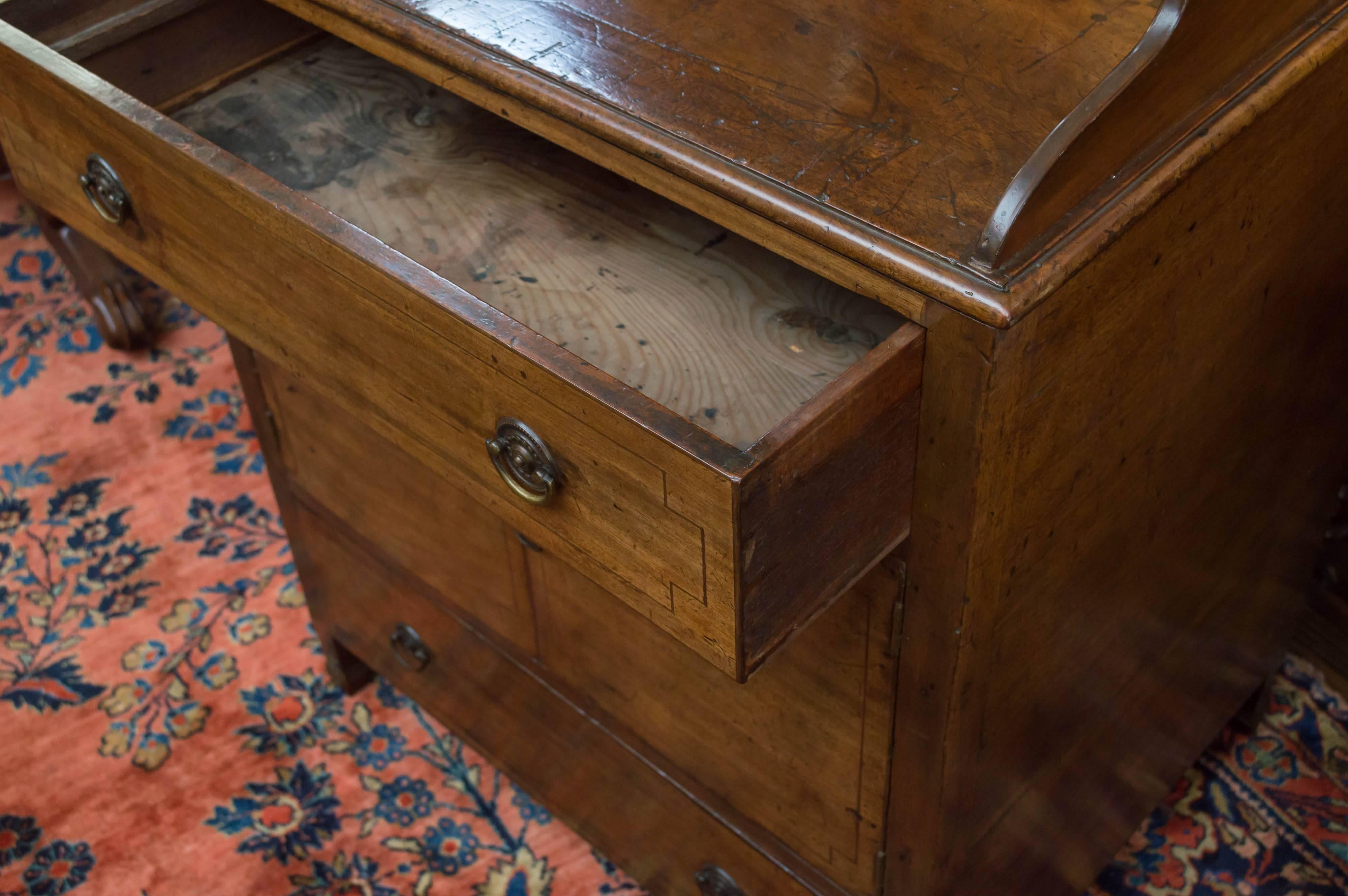 English mahogany Regency period cabinet, circa 1820
Tall gallery top on three sides with drawers above and below a centre cabinet.
Decorative line inlays on the drawers and cabinet doors.
Raised on small legs with spade feet. Retains the old