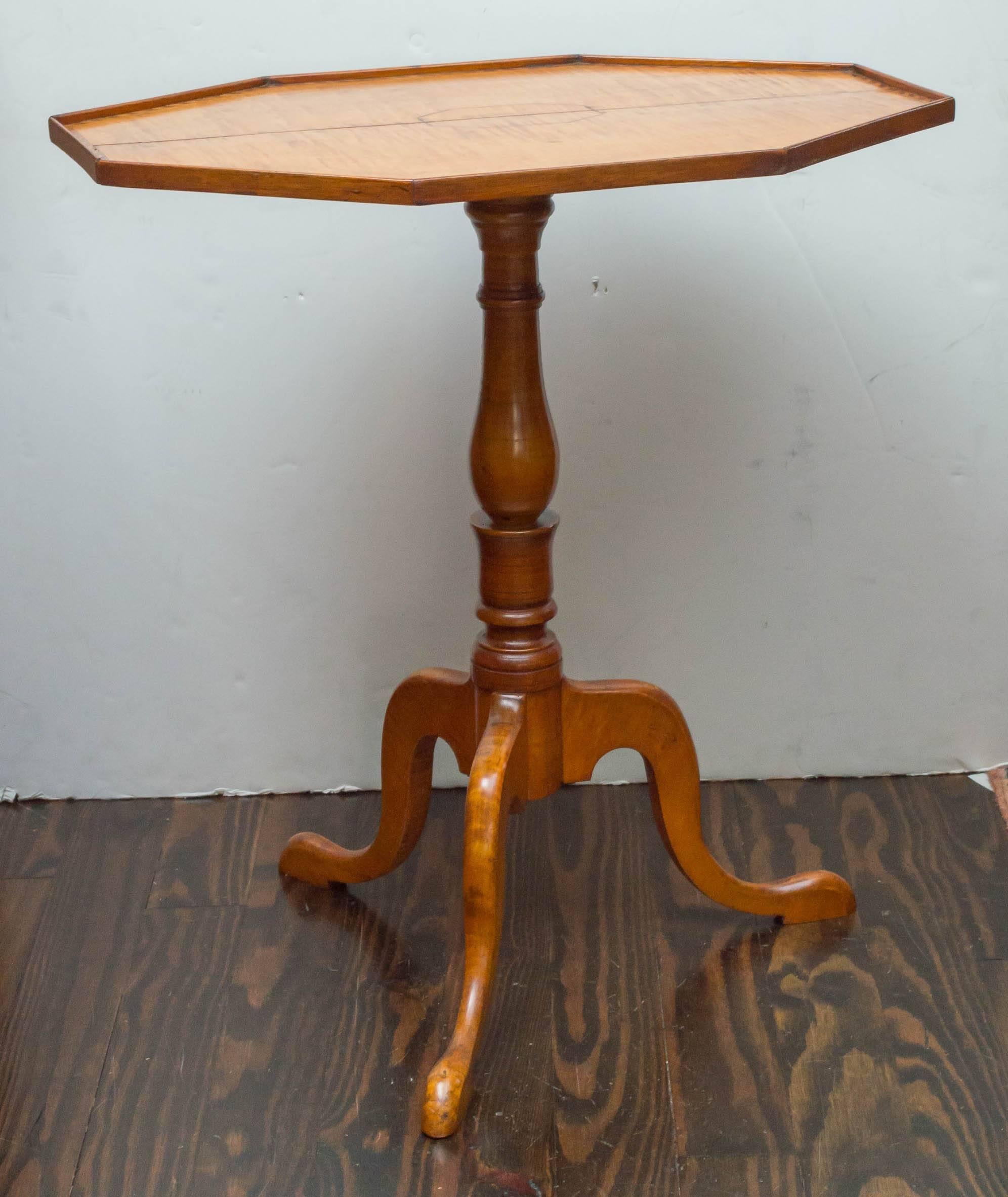 Late 18th century American tiger maple, tilt top, candle stand. The rectangular octagon shaped top is decorated with a walnut stripe inlaid border and central reserve. The two board matched top is made of solid boards with good figured stripes. A