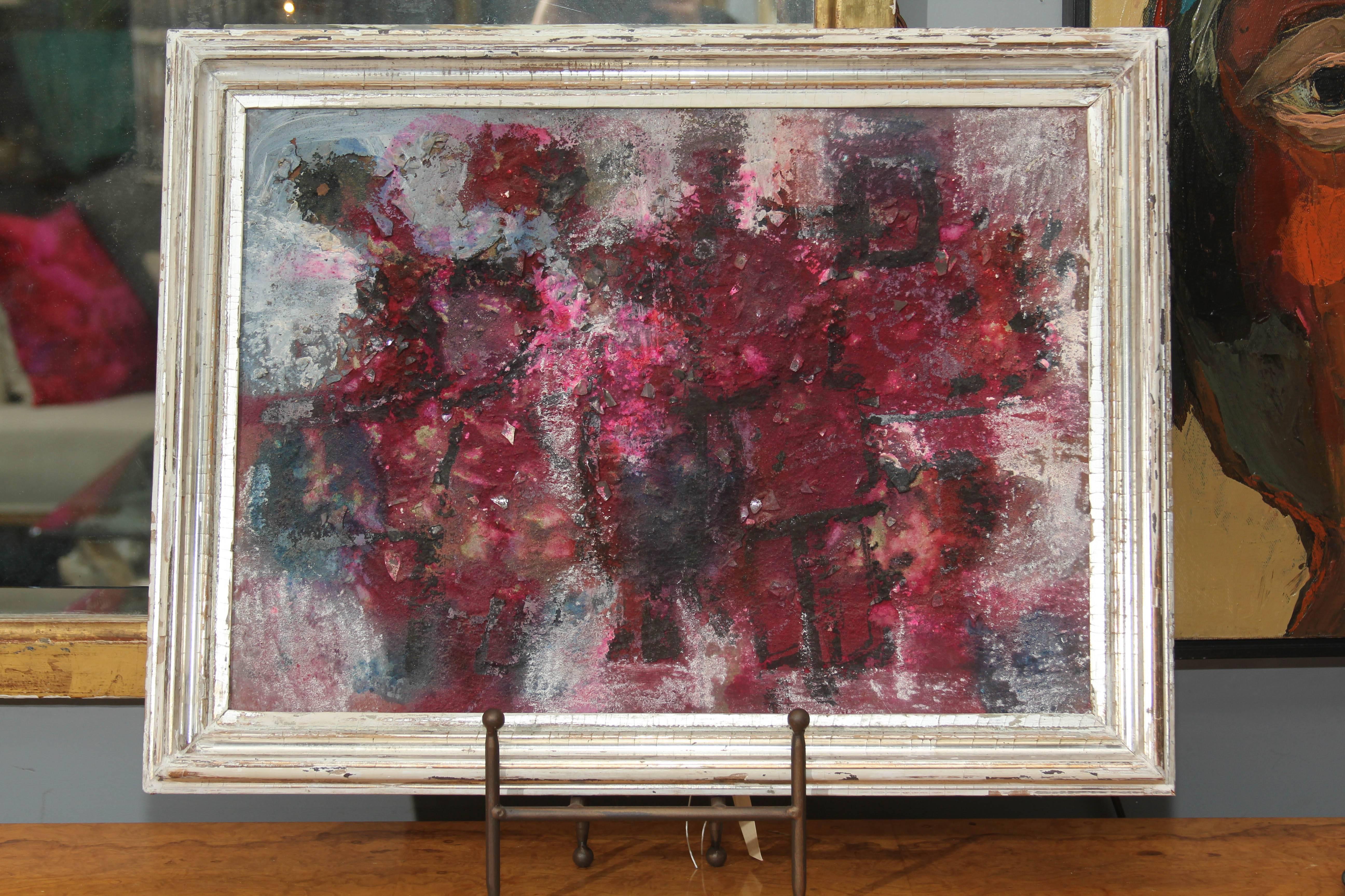 Mid-20th century abstract painting in varying shades of red with black and grey and bits of mirror suspended in the paint. Framed simply in silver gilt 19th century frame.