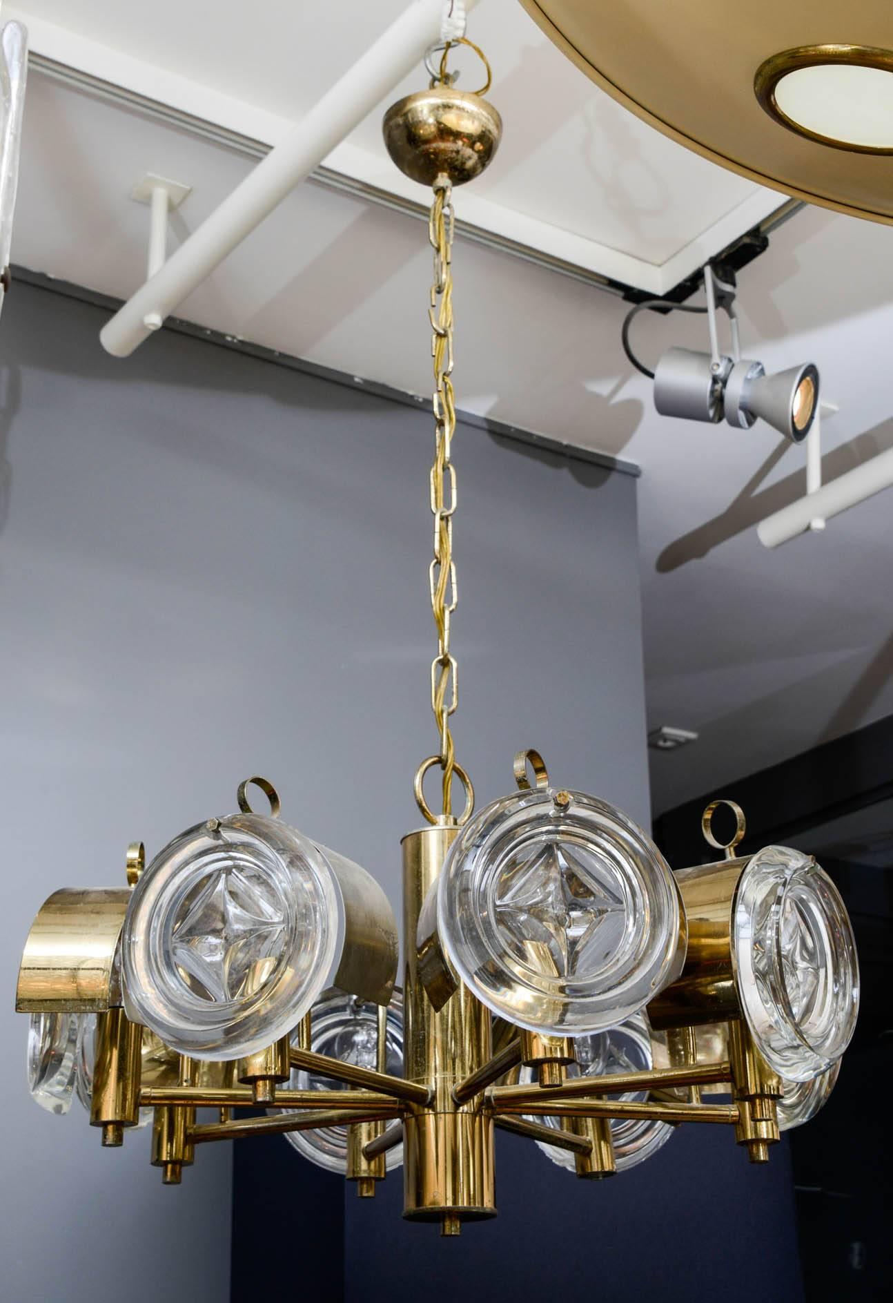 Small brass chandelier with eight arms, each ended by glass lenses to diffuse the light.